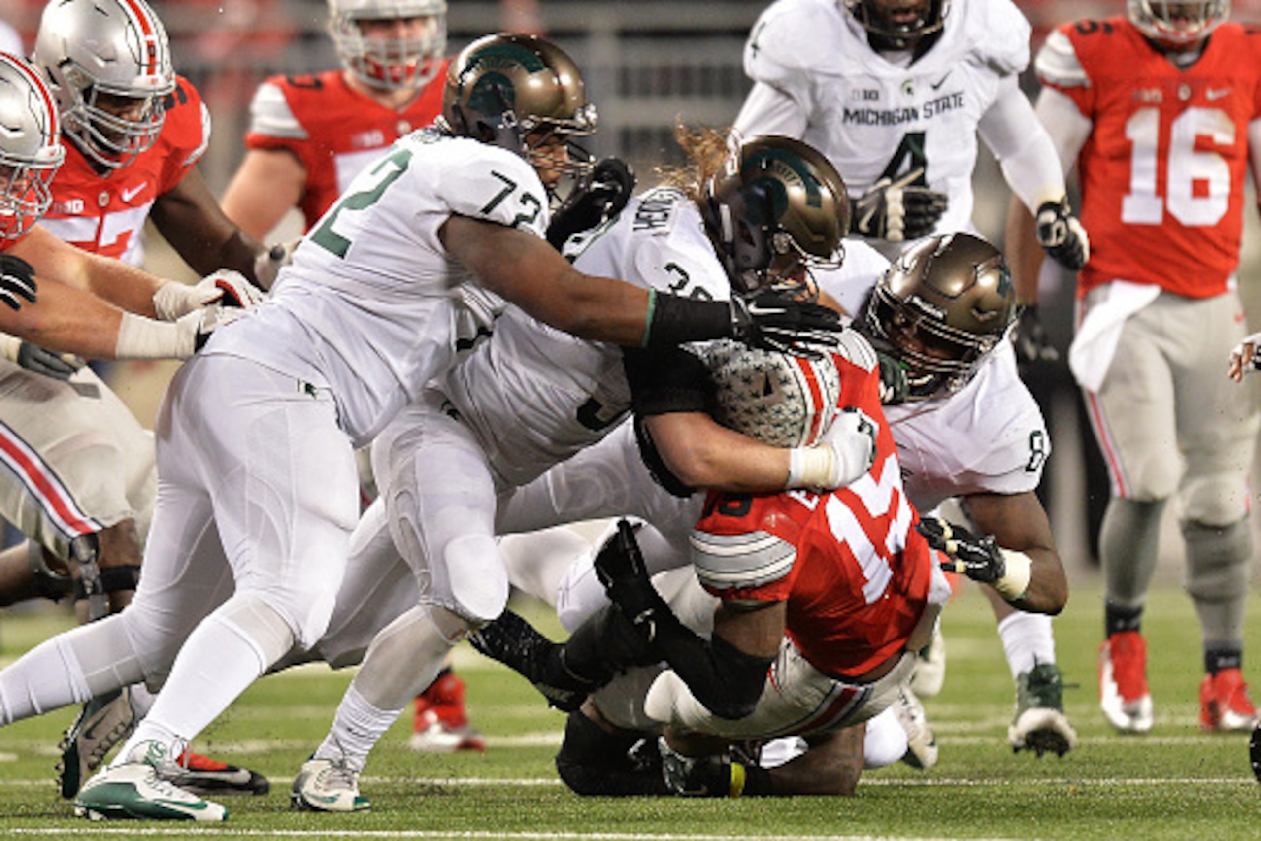 COLUMBUS, OH - NOVEMBER 21: Ezekiel Elliott #15 of the Ohio State Buckeyes is gang tackled by Craig Evans #72 of the Michigan State Spartans, Riley Bullough #30 of the Michigan State Spartans and Lawrence Thomas #8 of the Michigan State Spartans in the t COLUMBUS, OH - NOVEMBER 21: Ezekiel Elliott #15 of the Ohio State Buckeyes is gang tackled by Craig Evans #72 of the Michigan State Spartans, Riley Bullough #30 of the Michigan State Spartans and Lawrence Thomas #8 of the Michigan State Spartans in the t