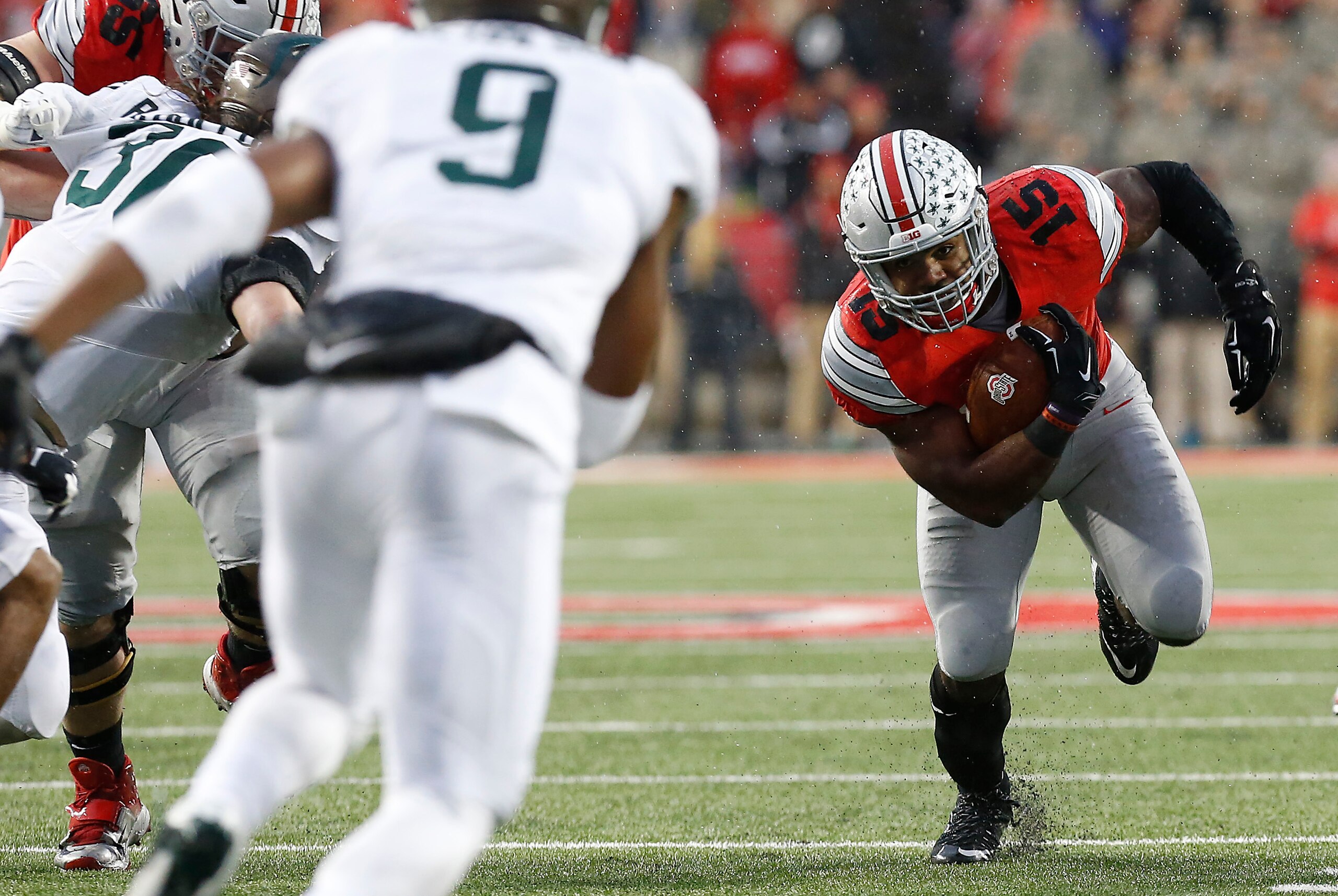 Nov 21, 2015; Columbus, OH, USA; Ohio State Buckeyes running back Ezekiel Elliott (15) carries the ball as Michigan State Spartans safety Montae Nicholson (9) and Spartans linebacker Riley Bullough (30) chase in the first quarter at Ohio Stadium. Mandator