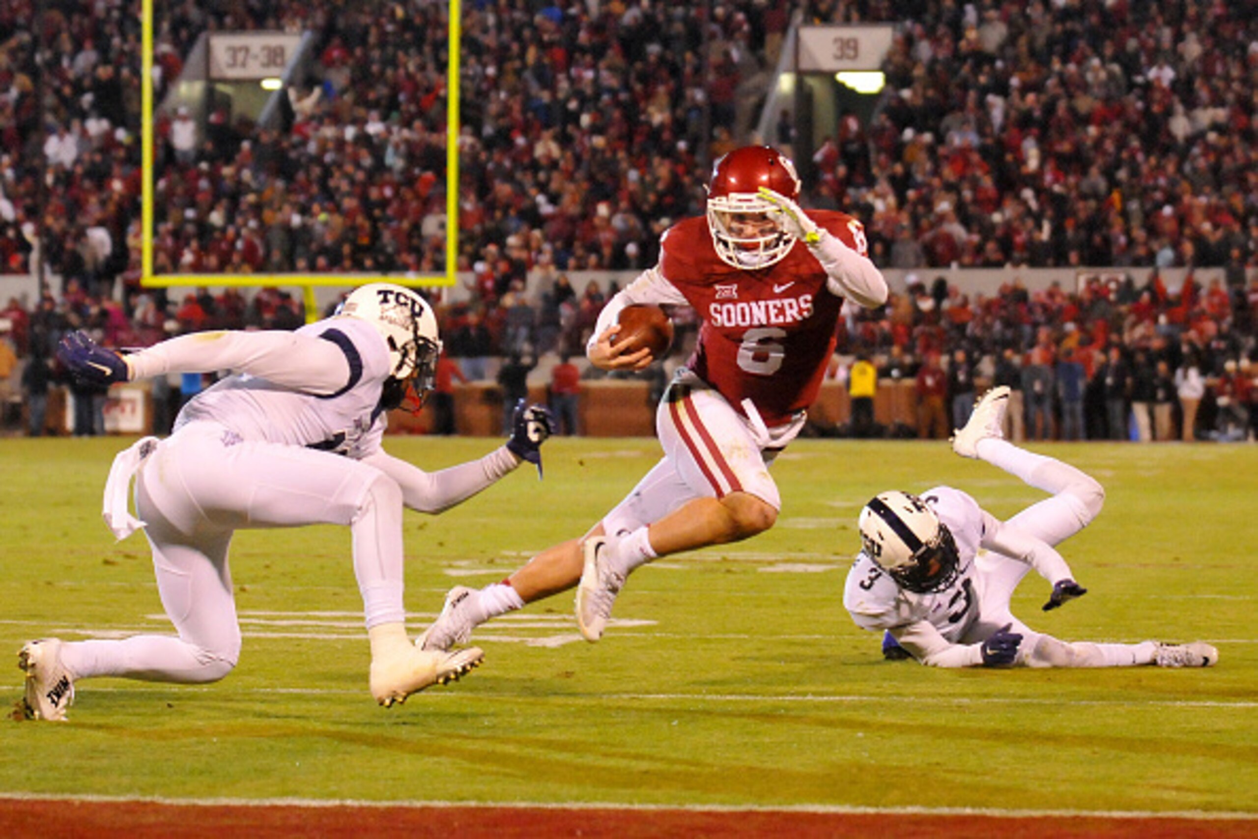 NORMAN, OK - NOVEMBER 21: Quarterback Baker Mayfield #6 of the Oklahoma Sooners tries to avoid tackles from cornerbacks Corry O'Meally #3 and Nick Orr #18 of the TCU Horned Frogs on November 21, 2015 at the Gaylord Family Oklahoma Memorial Stadium in Norm