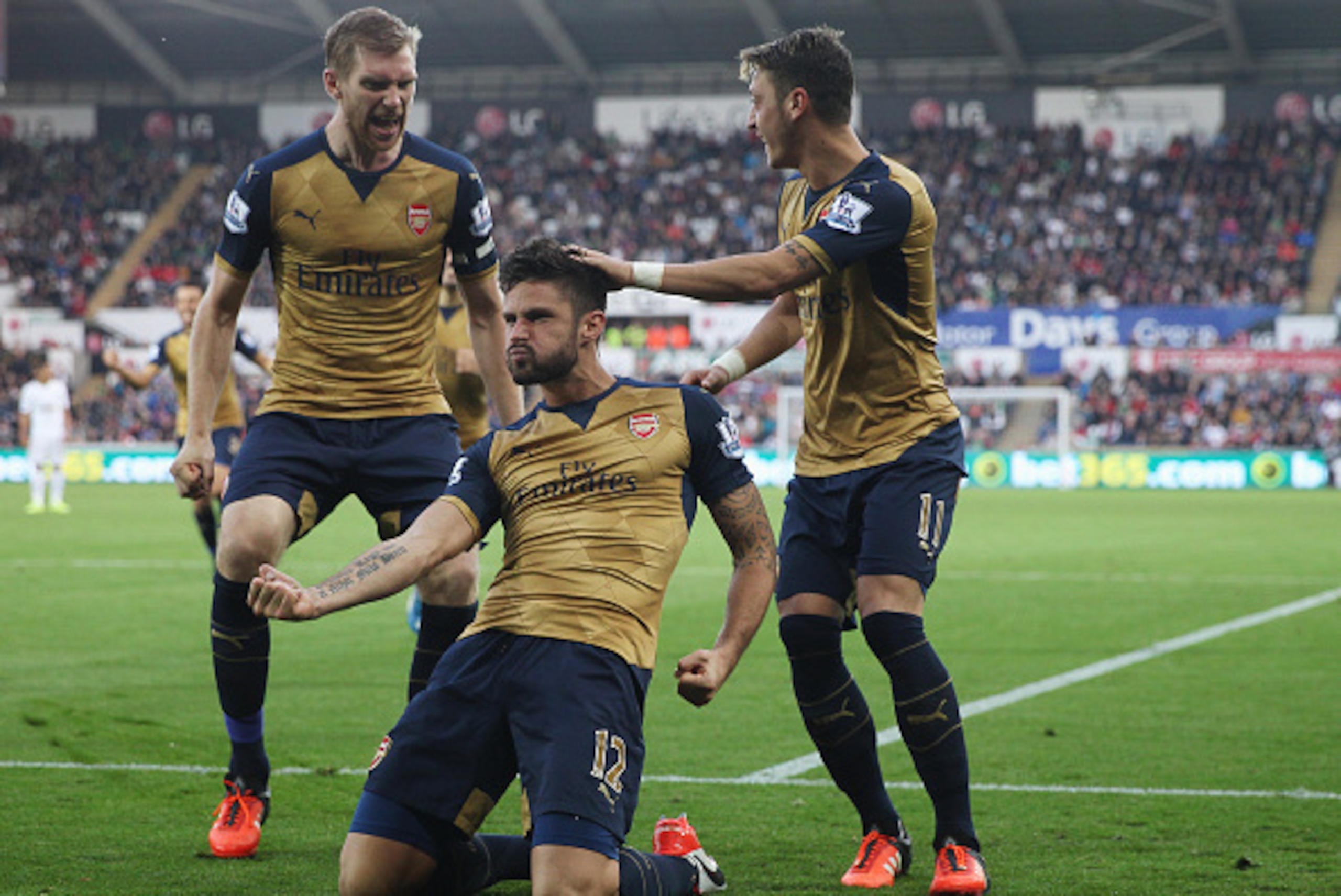 SWANSEA, WALES - OCTOBER 31: Olivier Giroud (C) of Arsenal celebrates scoring his team's first goal  with his team mates Per Mertesacker (L) and Mesut Ozil (R) during the Barclays Premier League match between Swansea City and Arsenal at Liberty Stadium on