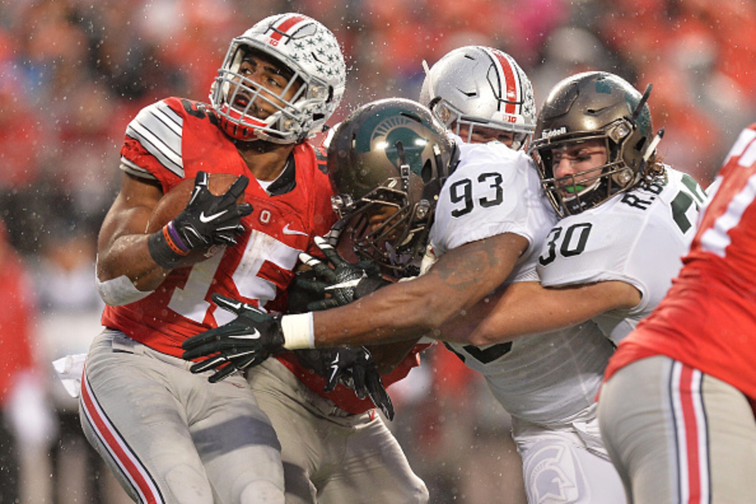 COLUMBUS, OH - NOVEMBER 21:  Ezekiel Elliott #15 of the Ohio State Buckeyes runs into Damon Knox #93 of the Michigan State Spartans and Riley Bullough #30 of the Michigan State Spartans at the line of scrimmage in the second quarter at Ohio Stadium on Nov