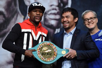 LAS VEGAS, NV - APRIL 29:  (L-R) WBC/WBA welterweight champion Floyd Mayweather Jr. and WBO welterweight champion Manny Pacquiao pose with a WBC championship belt as Pacquiao's trainer Freddie Roach looks on during a news conference at the KA Theatre at M