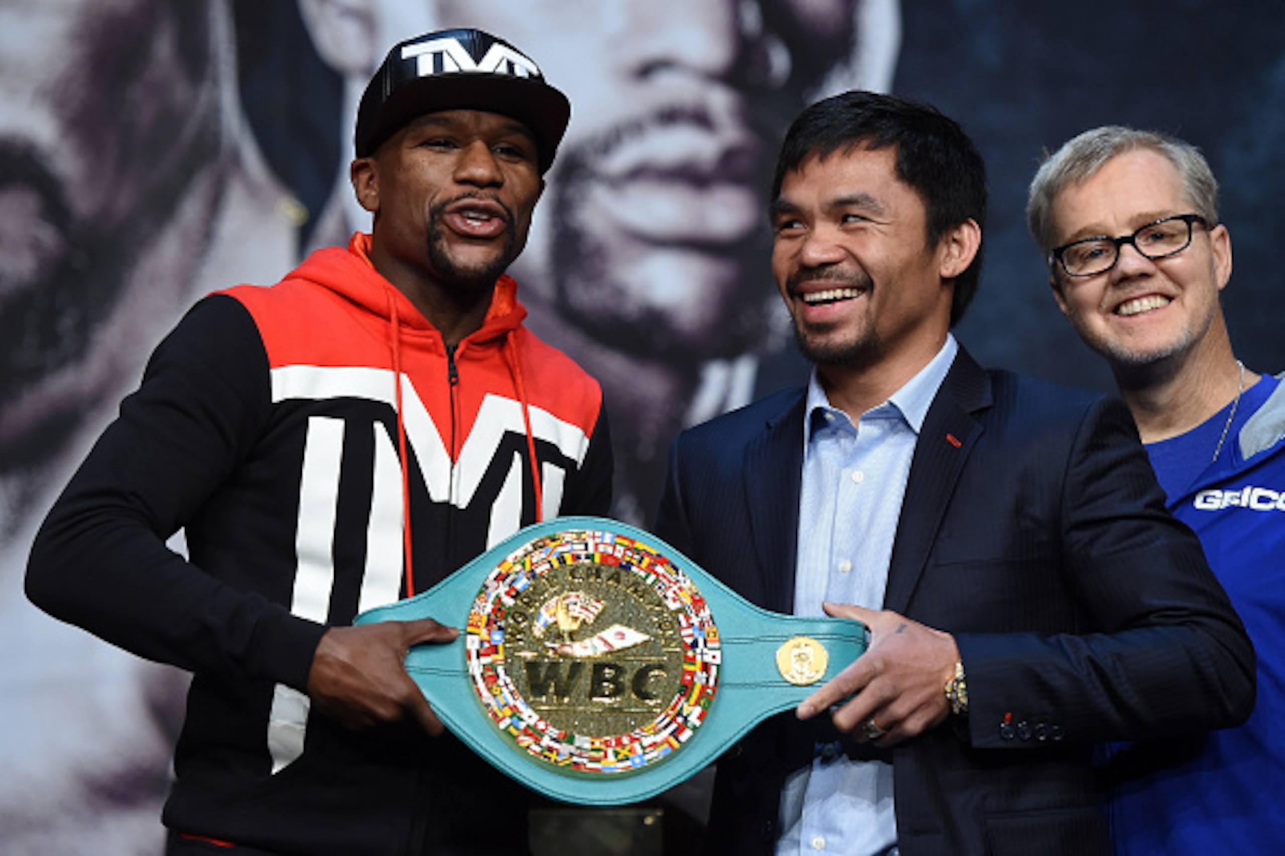 LAS VEGAS, NV - APRIL 29:  (L-R) WBC/WBA welterweight champion Floyd Mayweather Jr. and WBO welterweight champion Manny Pacquiao pose with a WBC championship belt as Pacquiao's trainer Freddie Roach looks on during a news conference at the KA Theatre at M