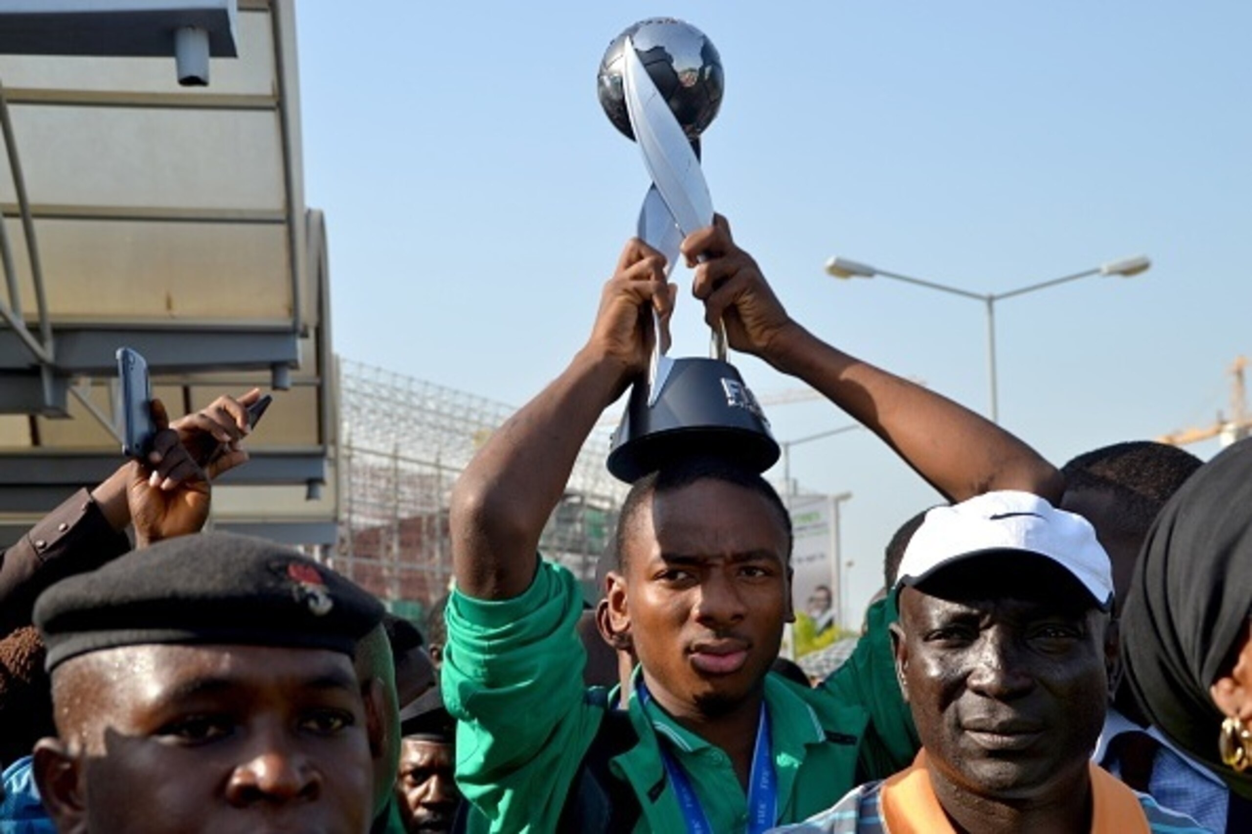 Nigeria's Kelechi Nwakali carries the Fifa Under-17 World Cup trophy on his head in the midst of a crowd gathered to receive the triumphant Nigeria U17 team, the Golden Eaglets, at Nnamdi Azikiwe Airport in Abuja, on November 11, 2015. Nigeria's Golden Ea