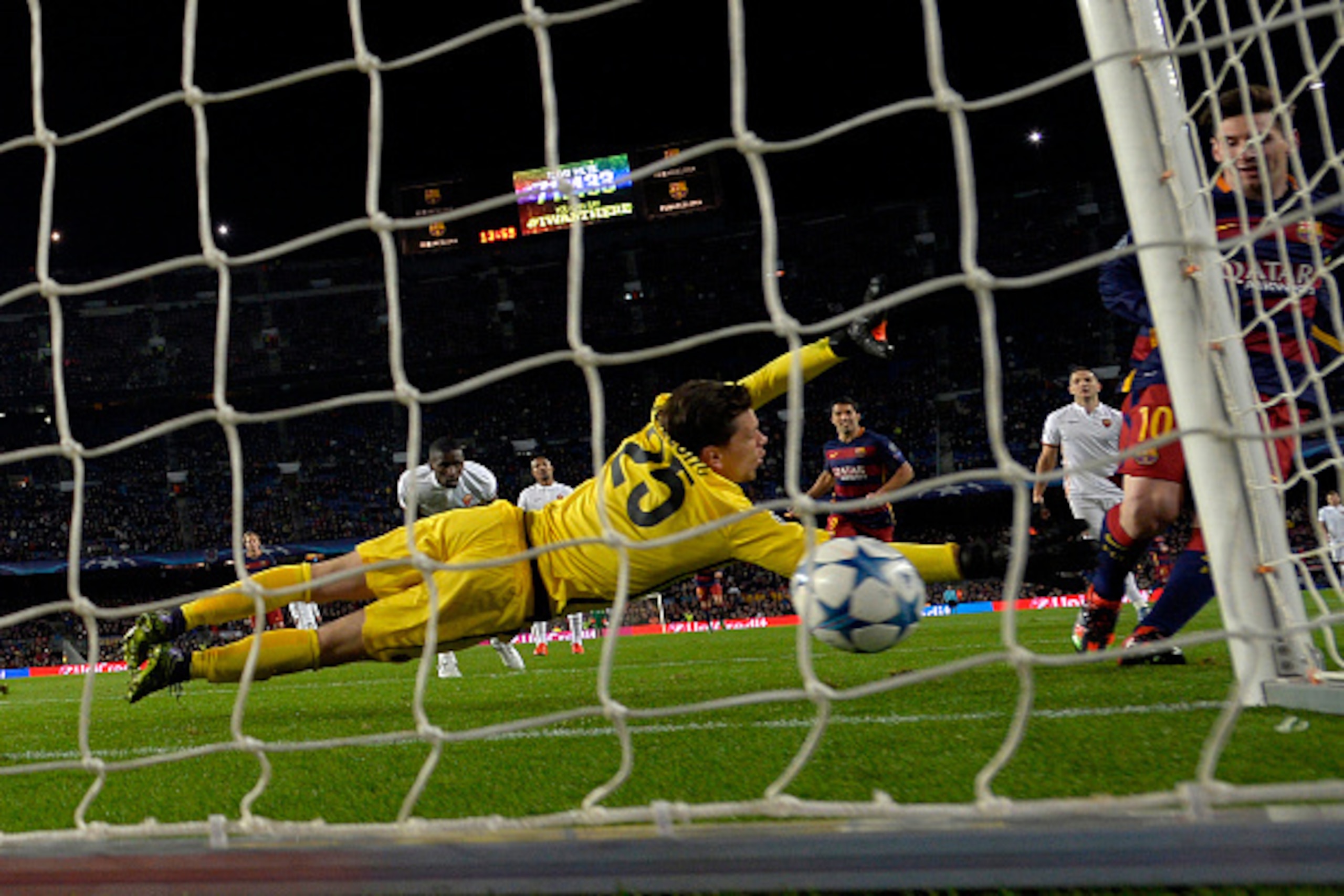 Barcelona's Argentinian forward Lionel Messi (R) scores a goal to Roma's Polish goalkeeper Wojciech Szczesny during the UEFA Champions League Group E football match FC Barcelona vs AS Roma at the Camp Nou stadium in Barcelona on November 24, 2015.   AFP P