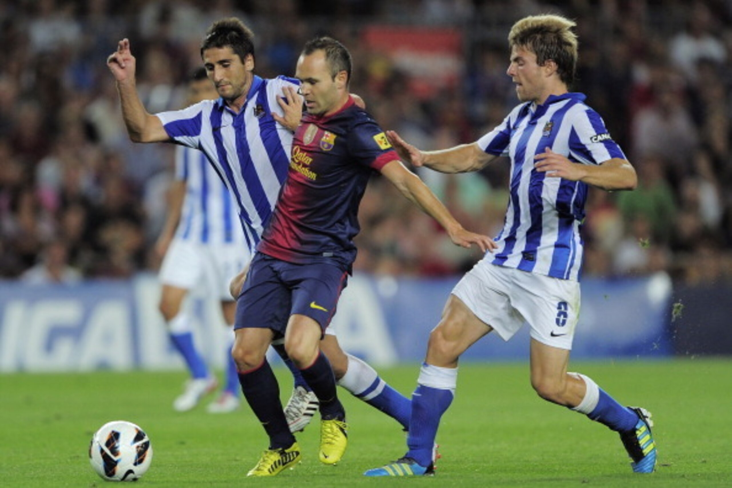 Real Sociedad's midfielder Markel Bergara Larranaga (L) and teammate midfielder Asier Illarramendi (R) vie for the ball with Barcelona's midfielder Andres Iniesta (C) during a Spanish League football match at the Camp Nou stadium in Barcelona, on August 1