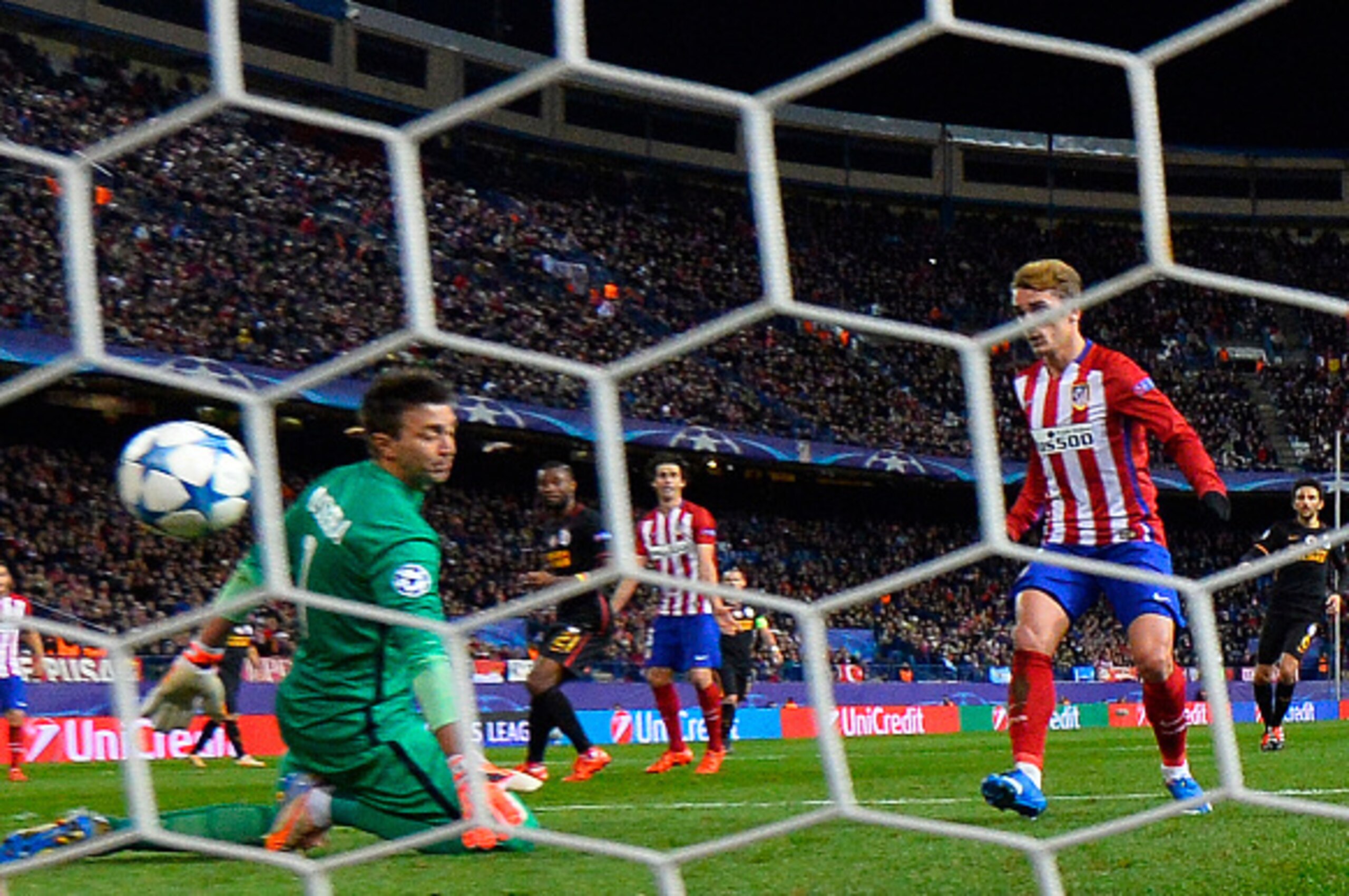 Atletico Madrid's French forward Antoine Griezmann (R) scores a goal as Galatasaray's Uruguayan goalkeeper Fernando Muslera kneels on the pitch during the UEFA Champions League Group C football match Club Atletico de Madrid vs Galatasaray AS at the Vicent