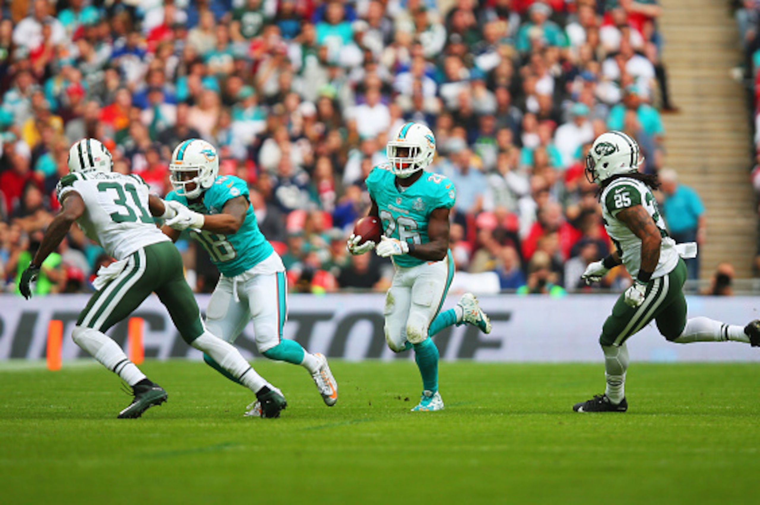LONDON, ENGLAND - OCTOBER 04:  Lamar Miller #26 of the Miami Dolphins is chased by Calvin Pryor #25 of the New York Jets during the game at Wembley Stadium on October 4, 2015 in London, England.  (Photo by Bryn Lennon/Getty Images)