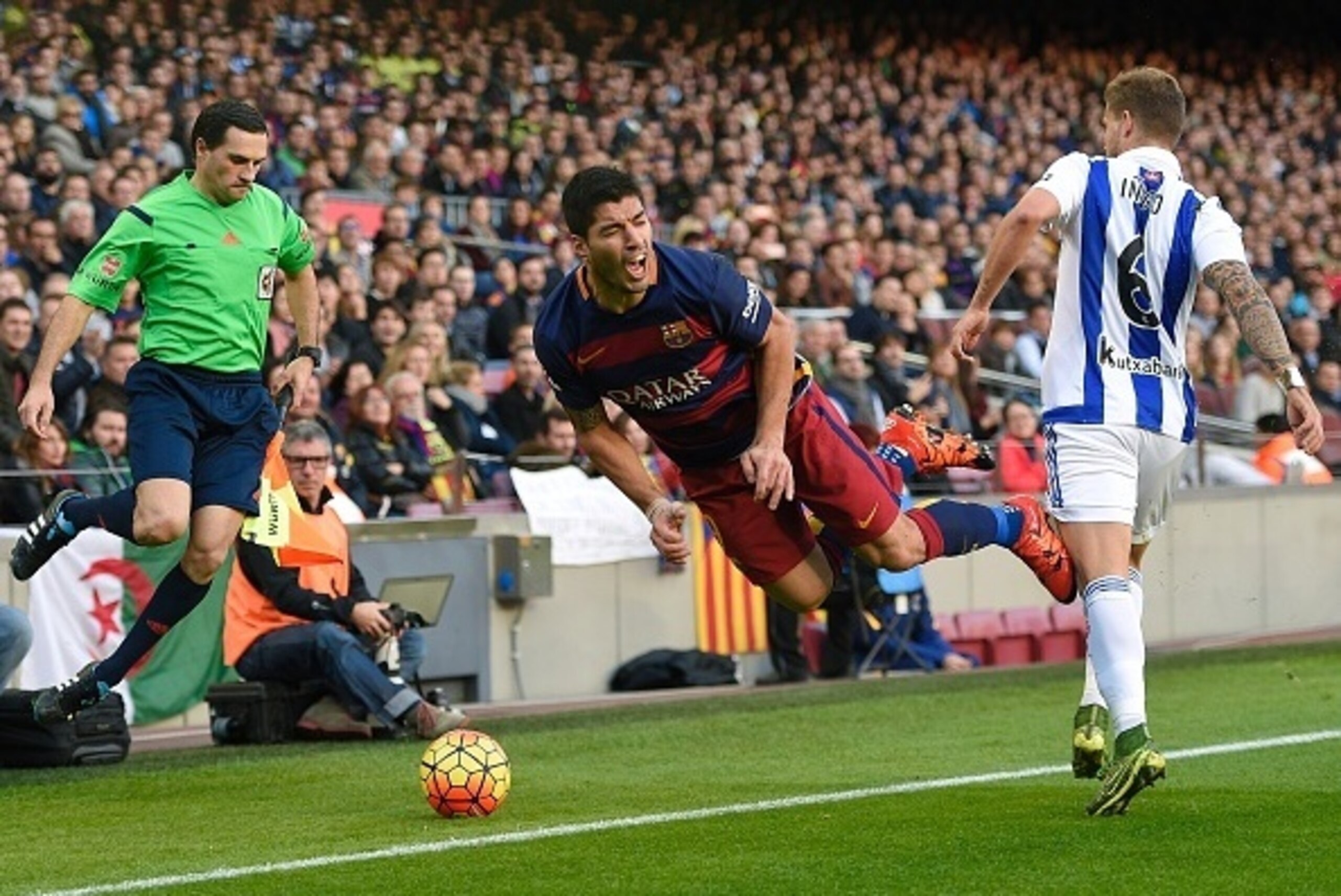 Barcelona's Uruguayan forward Luis Suarez (C) falls past Real Sociedad's defender Inigo Martinez Berridi (R) during the Spanish league football match FC Barcelona vs Real Sociedad de Futbol at the Camp Nou stadium in Barcelona on November 28, 2015.   AFP 
