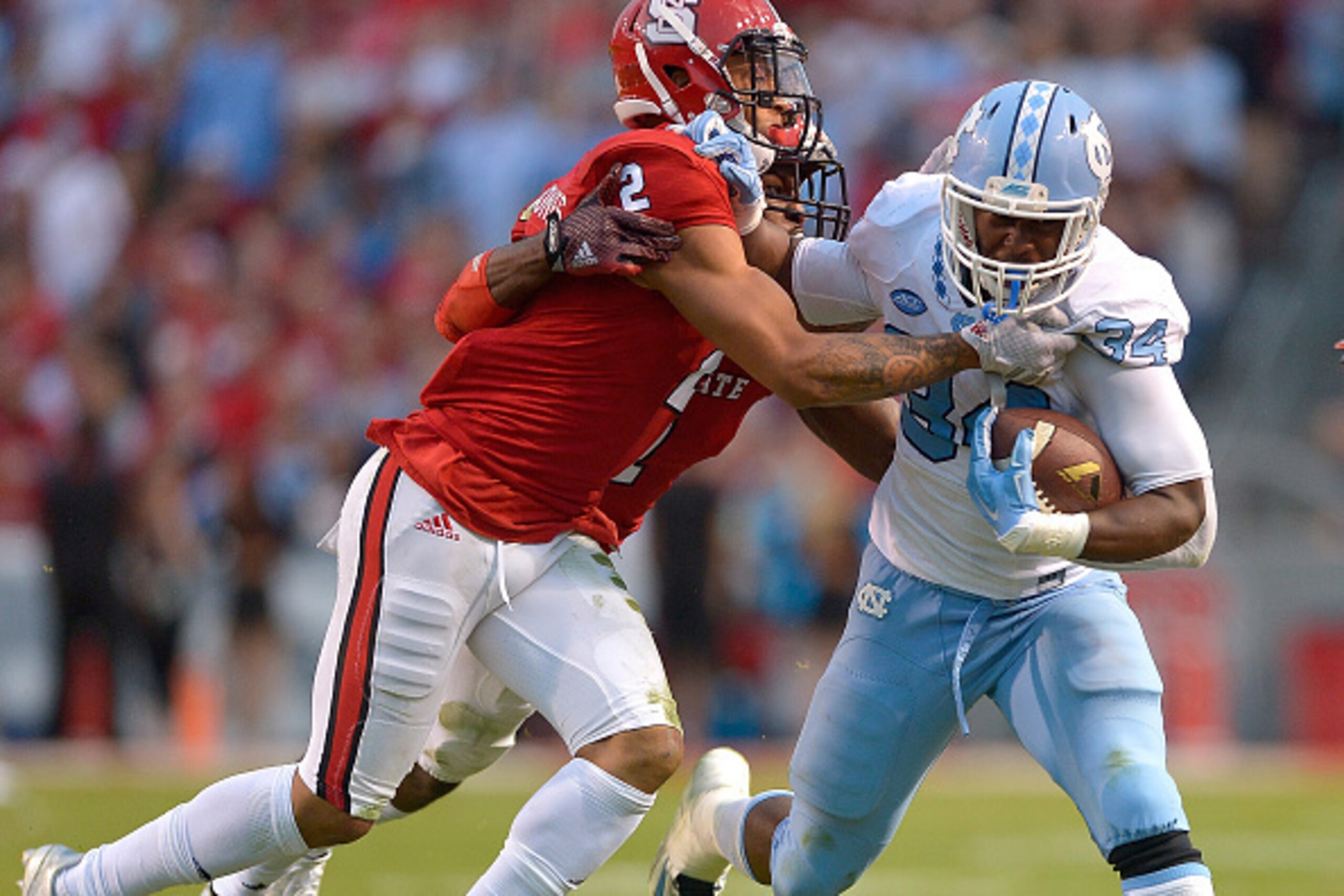 RALEIGH, NC - NOVEMBER 28:  Josh Jones #2 and Hakim Jones #1 of the North Carolina State Wolfpack tackle Elijah Hood #34 of the North Carolina Tar Heels during their game at Carter-Finley Stadium on November 28, 2015 in Raleigh, North Carolina.  (Photo by