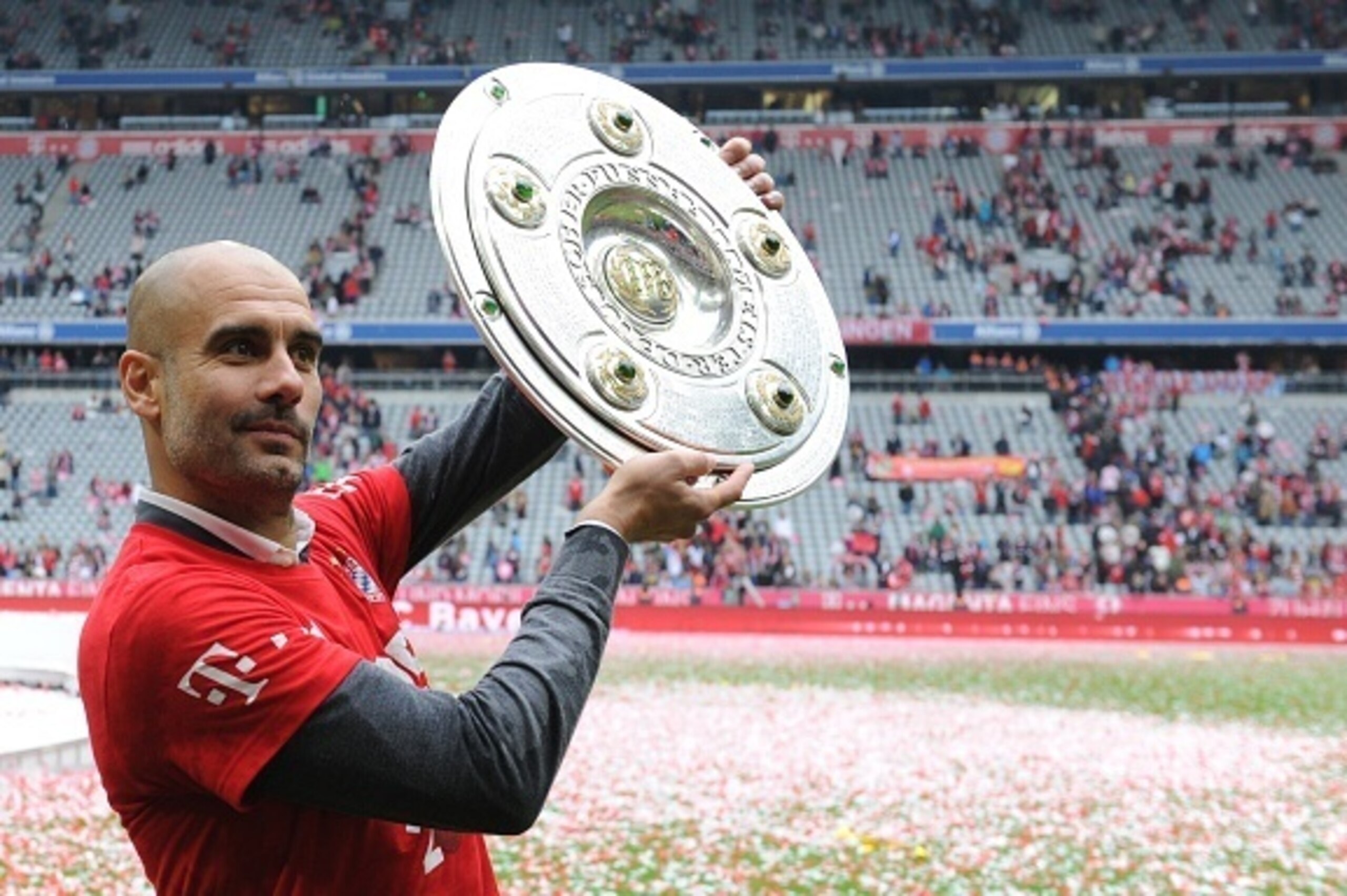 Bayern Munich's Spanish headcoach Pep Guardiola holds the trophy as they celebrate winning their 25th Bundesliga title after the German first division Bundesliga football match FC Bayern Munich vs 1 FSV Mainz 05 at the Allianz Arena in Munich, southern Ge