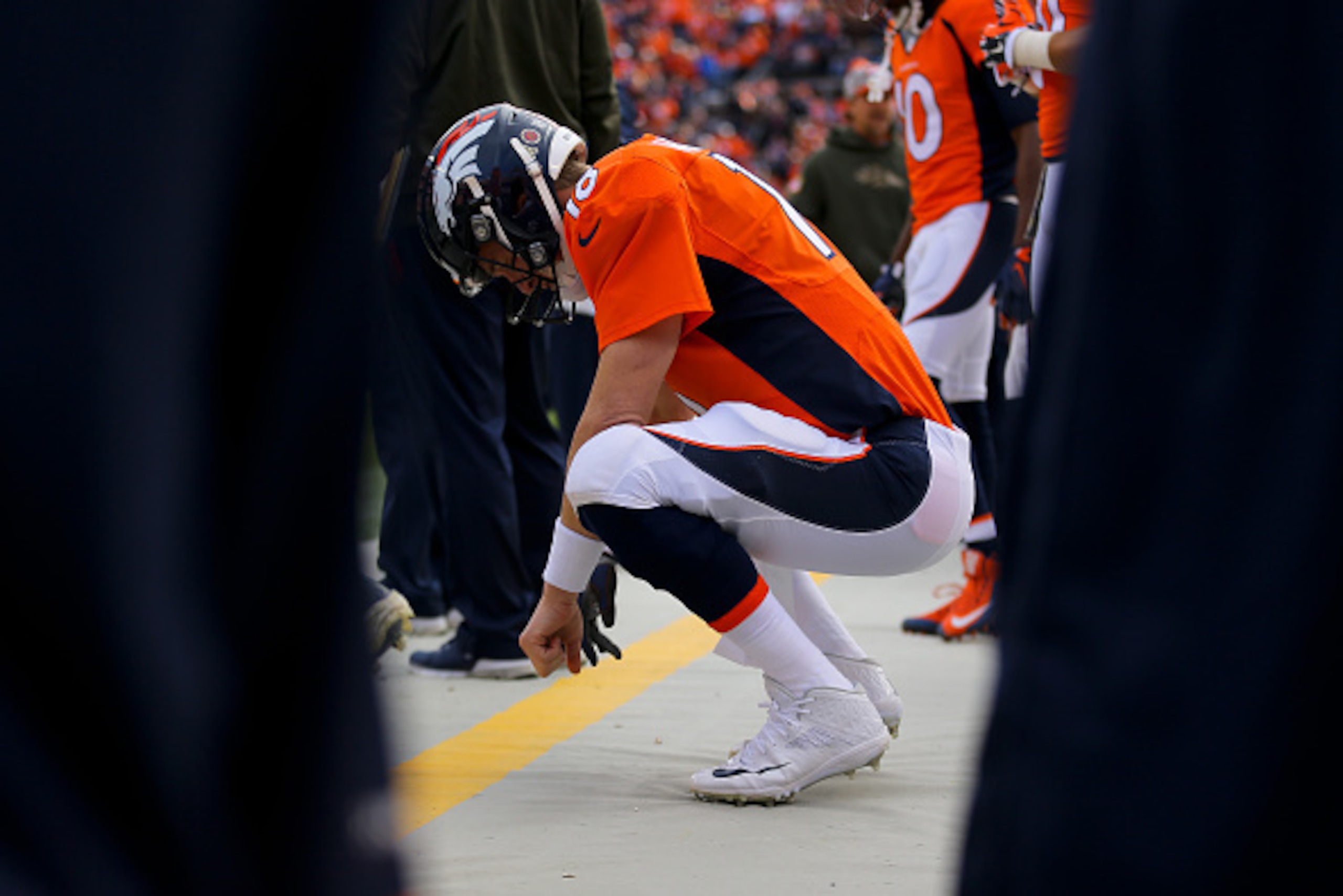DENVER, CO - NOVEMBER 15:  Quarterback Peyton Manning #18 of the Denver Broncos crouches on the sidelines during a game against the Kansas City Chiefs at Sports Authority Field Field at Mile High on November 15, 2015 in Denver, Colorado. (Photo by Justin 
