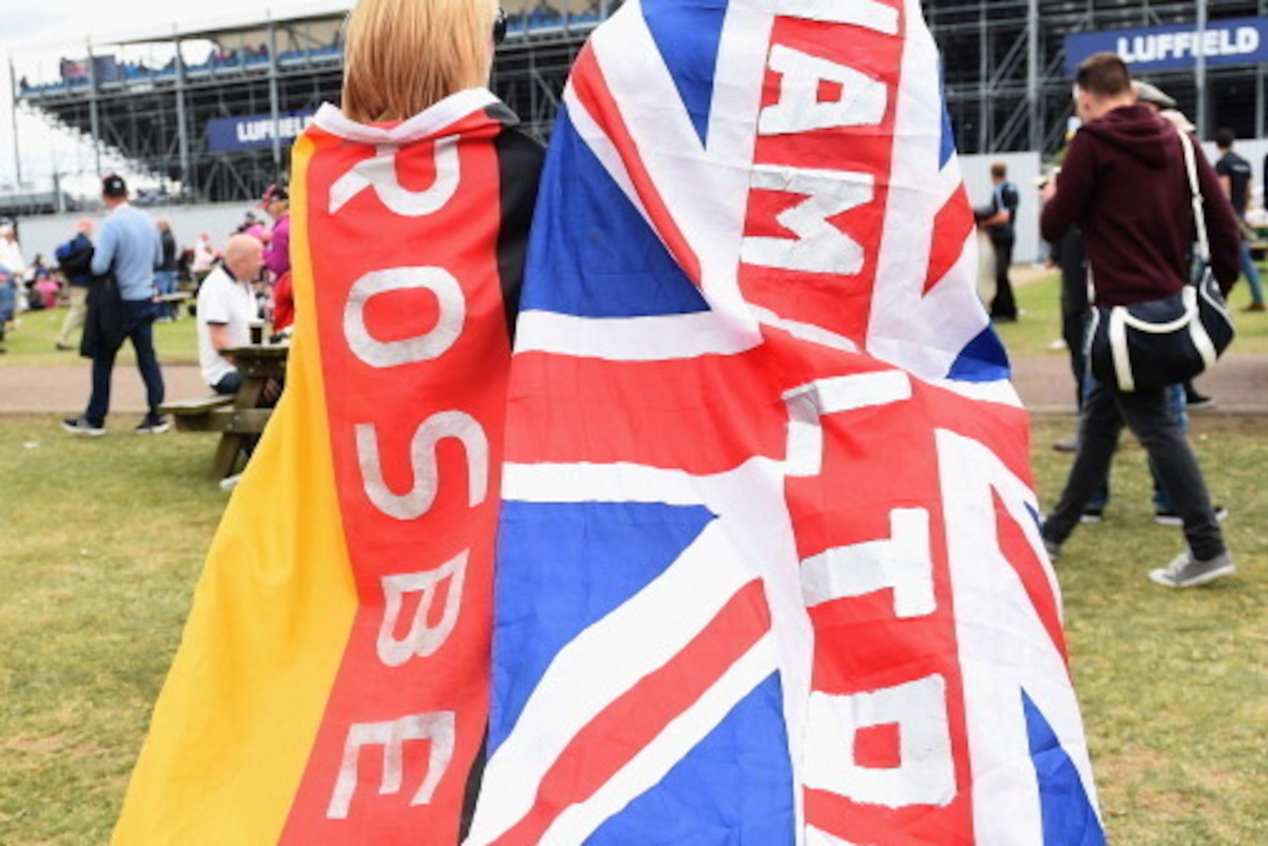 NORTHAMPTON, ENGLAND - JULY 06:  Two fans wearing Nico Rosberg and Lewis Hamilton named flags walk into the stands during the British Formula One Grand Prix at Silverstone Circuit on July 6, 2014 in Northampton, United Kingdom.  (Photo by Christopher Lee/
