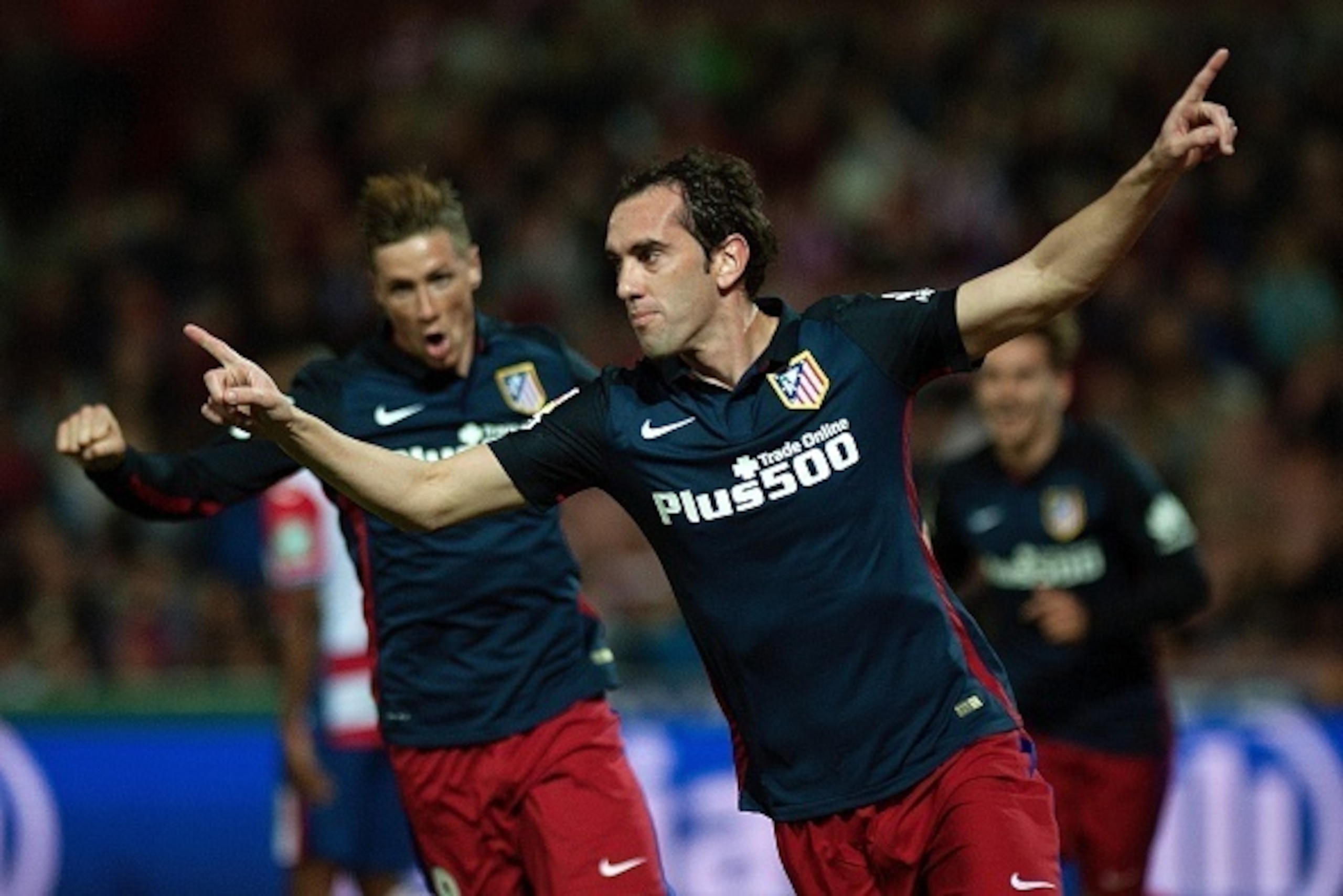 Atletico Madrid's Uruguayan defender Diego Godin (R) celebrates a goal during the Spanish league football match Granada FC VS Club Atletico de Madrid at Nuevo Los Carmenes stadium in Granada on December 5, 2015.   AFP PHOTO / JORGE GUERRERO / AFP / Jorge 