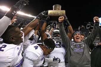 CHICAGO, IL - NOVEMBER 28:  Head coach Pat Fitzgerald of the Northwestern Wildcats (R) celebrates with his team including (L-R) Traveon Henry #2, Solomon Vault #4 and Deonte Gibson #13  as they hold the 'Land of Lincoln' trophy after a win over the Illino