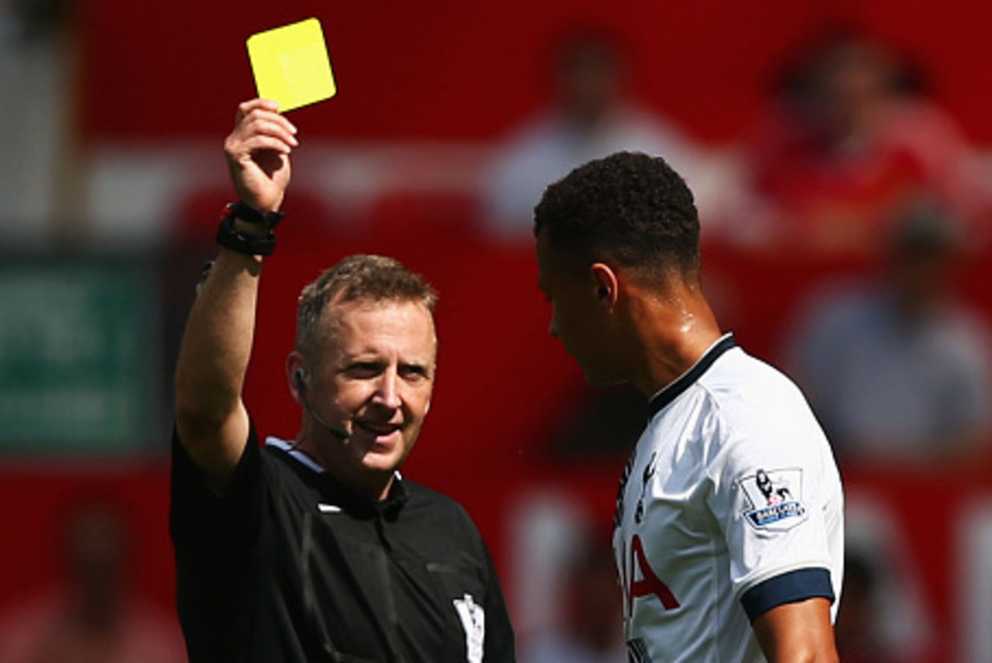 MANCHESTER, ENGLAND - AUGUST 08: Dele Alli of Tottenham Hotspur is shown a yellow card by referee Jonathan Moss during the Barclays Premier League match between Manchester United and Tottenham Hotspur at Old Trafford on August 8, 2015 in Manchester, Engla