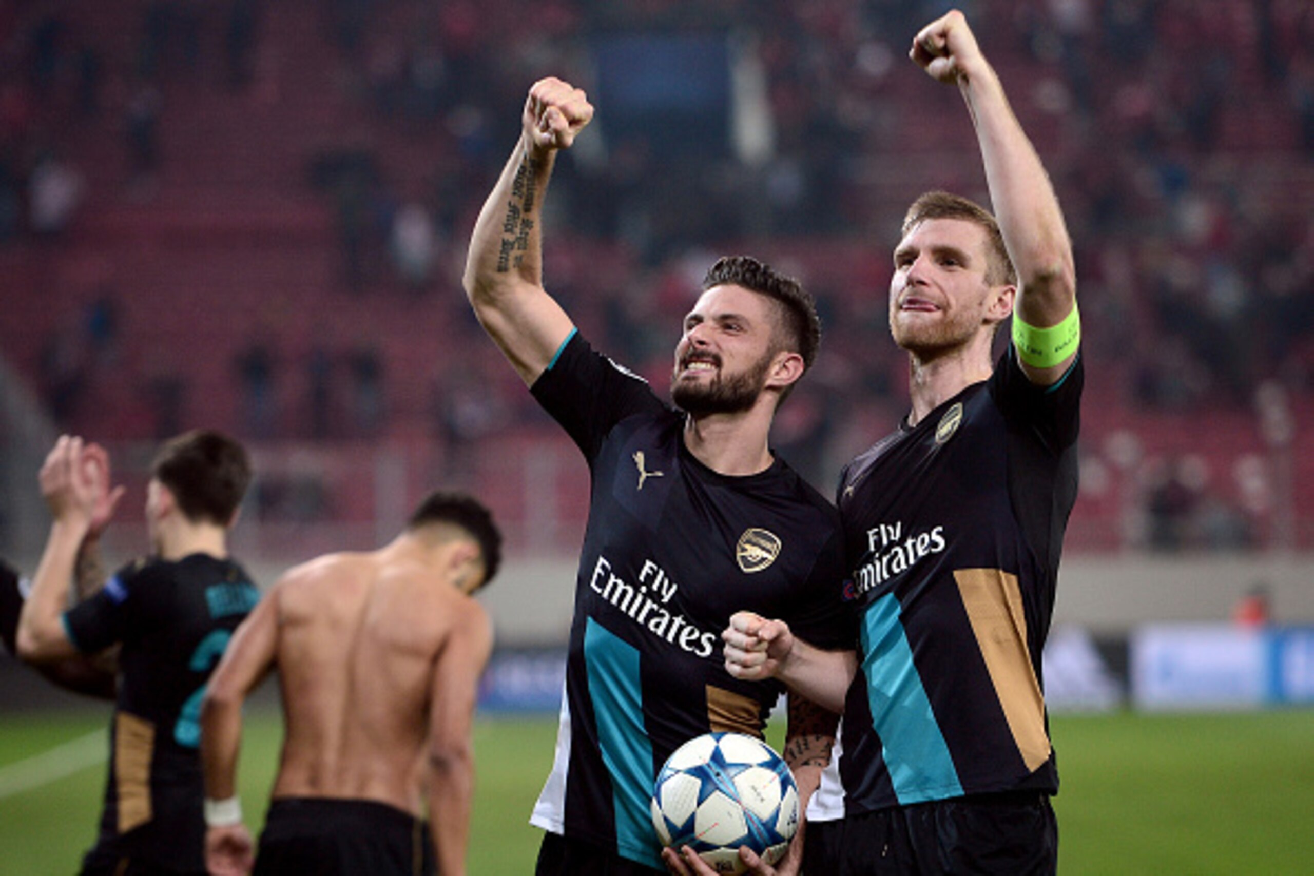 Arsenal's French forward Olivier Giroud (L)and Arsenal's German defender Per Mertesacker celebrate after the UEFA Champions League Group F football match between Olympiacos and Arsenal at the Georgios Karaiskakis Stadium in Piraeus near Athens on December