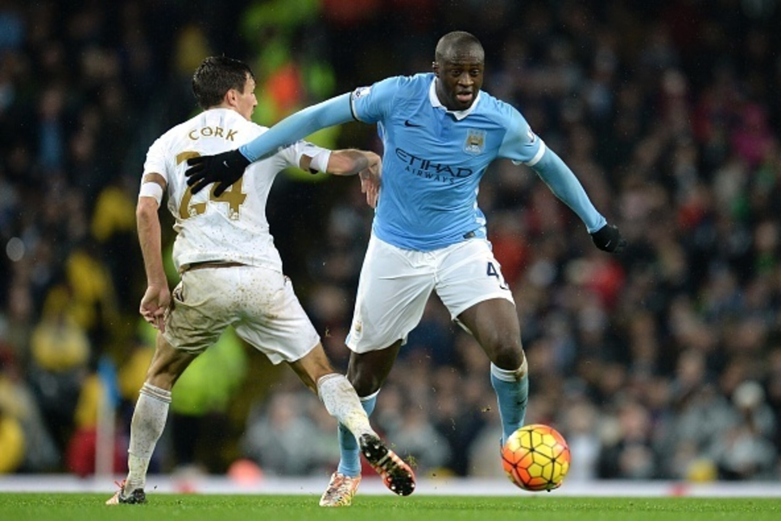 Manchester City's Ivorian midfielder and captain Yaya Toure (R) beats Swansea City's English midfielder Jack Cork (L) during the English Premier League football match between Manchester City and Swansea City at the Etihad Stadium in Manchester, north west