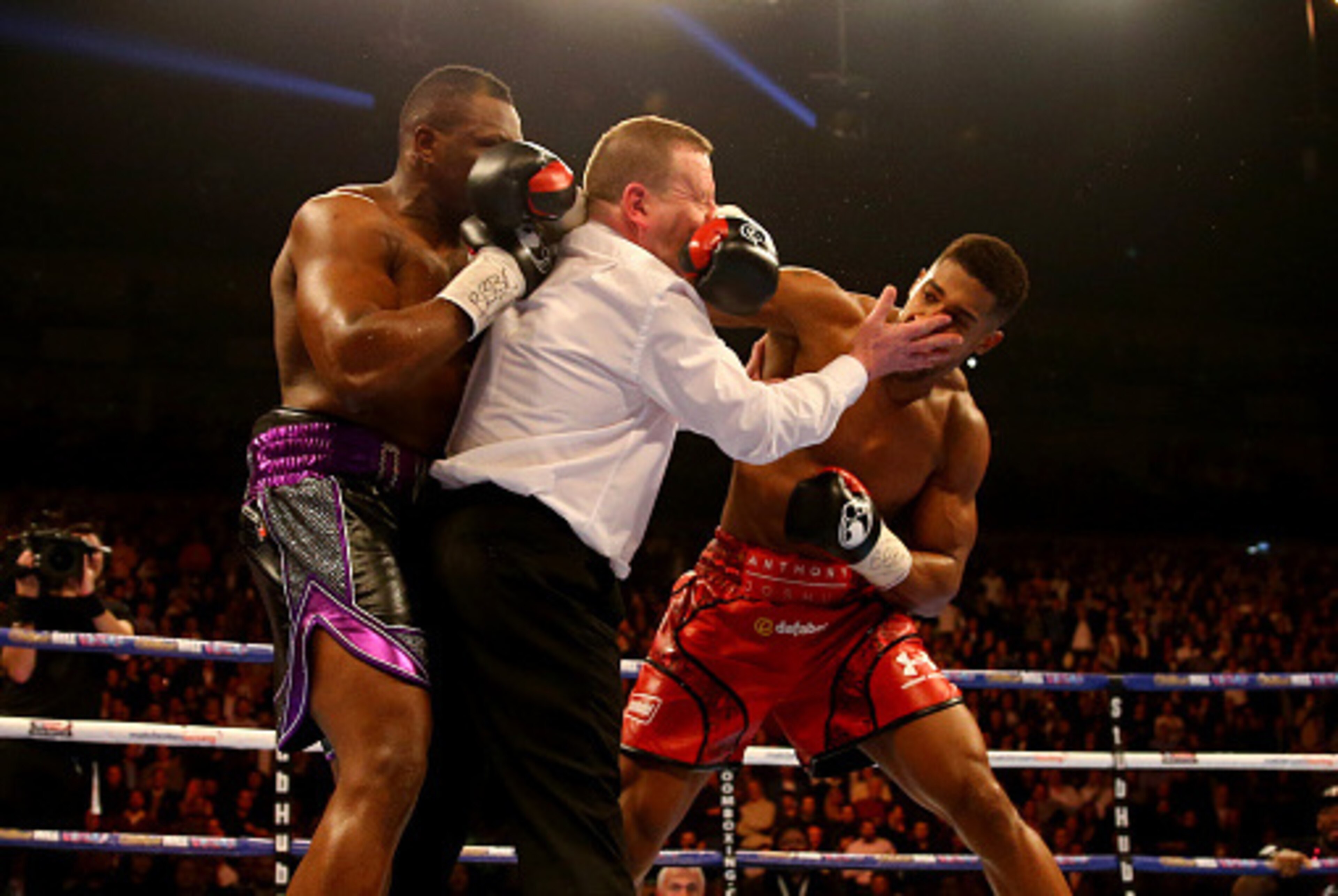 LONDON, ENGLAND - DECEMBER 12:  Anthony Joshua (R) throws a punch after the bell at the end of the first round as the referee intervenes during the British and Commonwealth heavyweight title contest against Dillian Whyte (L) at the Matchroom Boxing promot