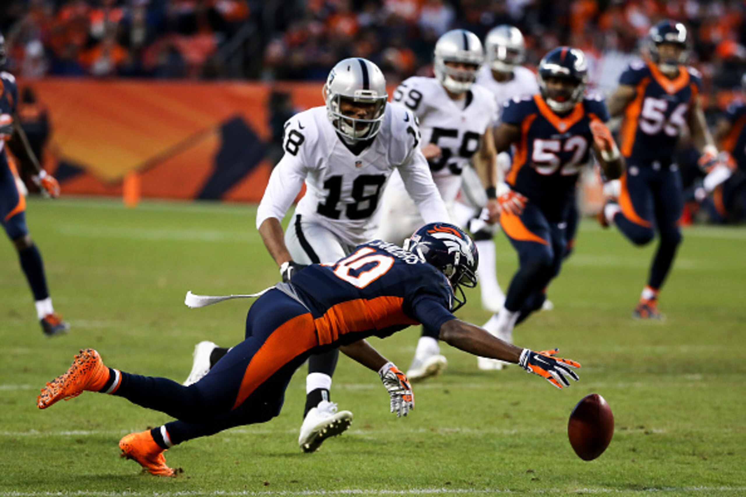 DENVER, CO - DECEMBER 13:  Wide receiver Emmanuel Sanders #10 of the Denver Broncos fumbles a punt return attempt in the fourth quarter of a game as wide receiver Andre Holmes #18 of the Oakland Raiders covers the play at Sports Authority Field at Mile Hi