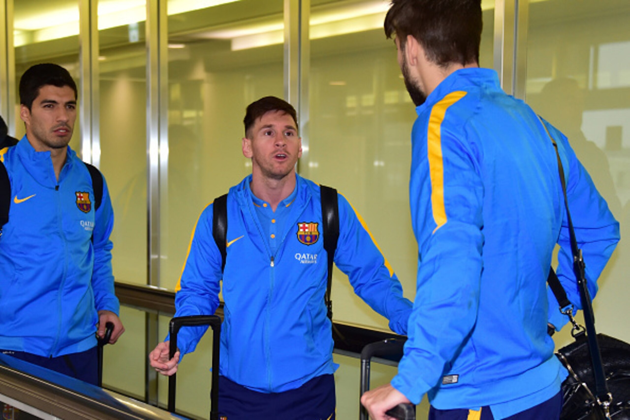 Spain's FC Barcelona football team members (L-R) Luis Suarez, Lionel Messi and Gerard Piquet chat with each other upon their arrival at the Narita international airport in Narita, suburban Tokyo on December 14, 2015. FC Barcelona will paly against Asian c