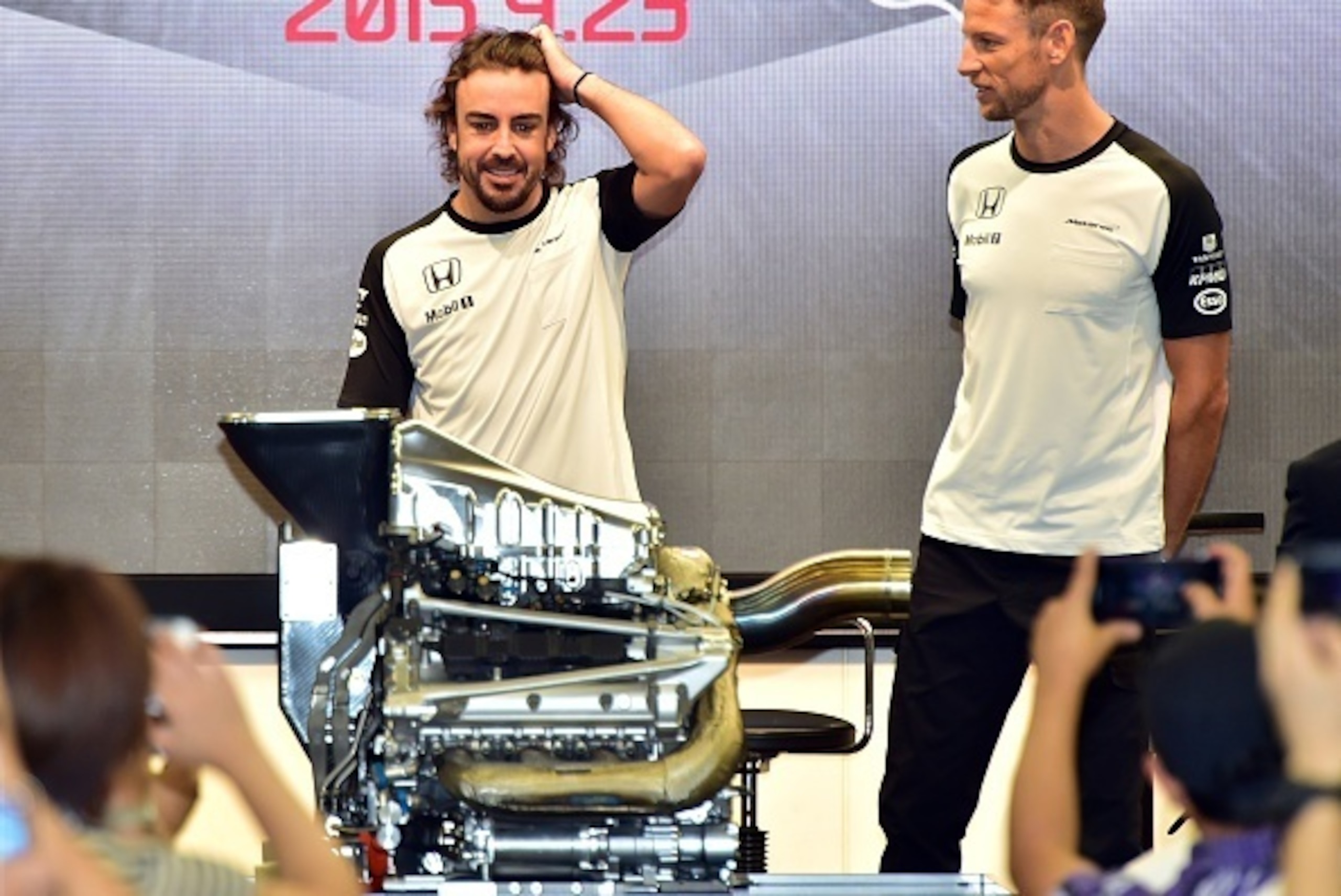 McLaren Honda drivers Fernando Alonso (L) and Jenson Button look at Honda's new power unit at a fan meeting at the Honda headquarters in Tokyo on September 23, 2015. The Japanese Grand Prix will be held at Suzuka circuit in Mie prefecture from September 2