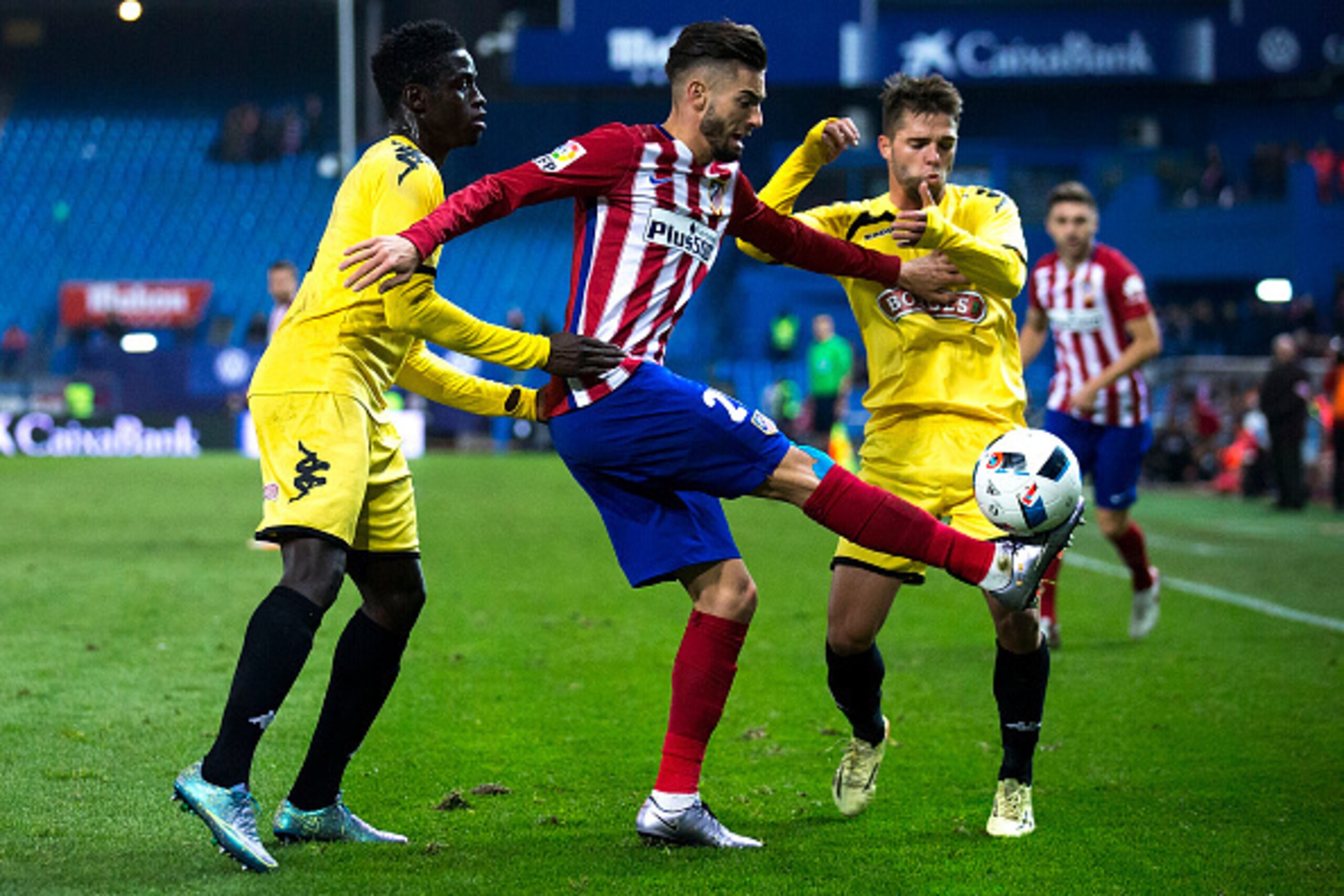 MADRID, SPAIN - DECEMBER 17: Yannick Carrasco (2ndL) of Atletico de Madrid competes for the ball with Eliseu Cassama (L) of CF Reus during the Copa del Rey Round of 32 match between Club Atletico Madrid and CF Reus Deportiu at Vicente Claderon stadium on 