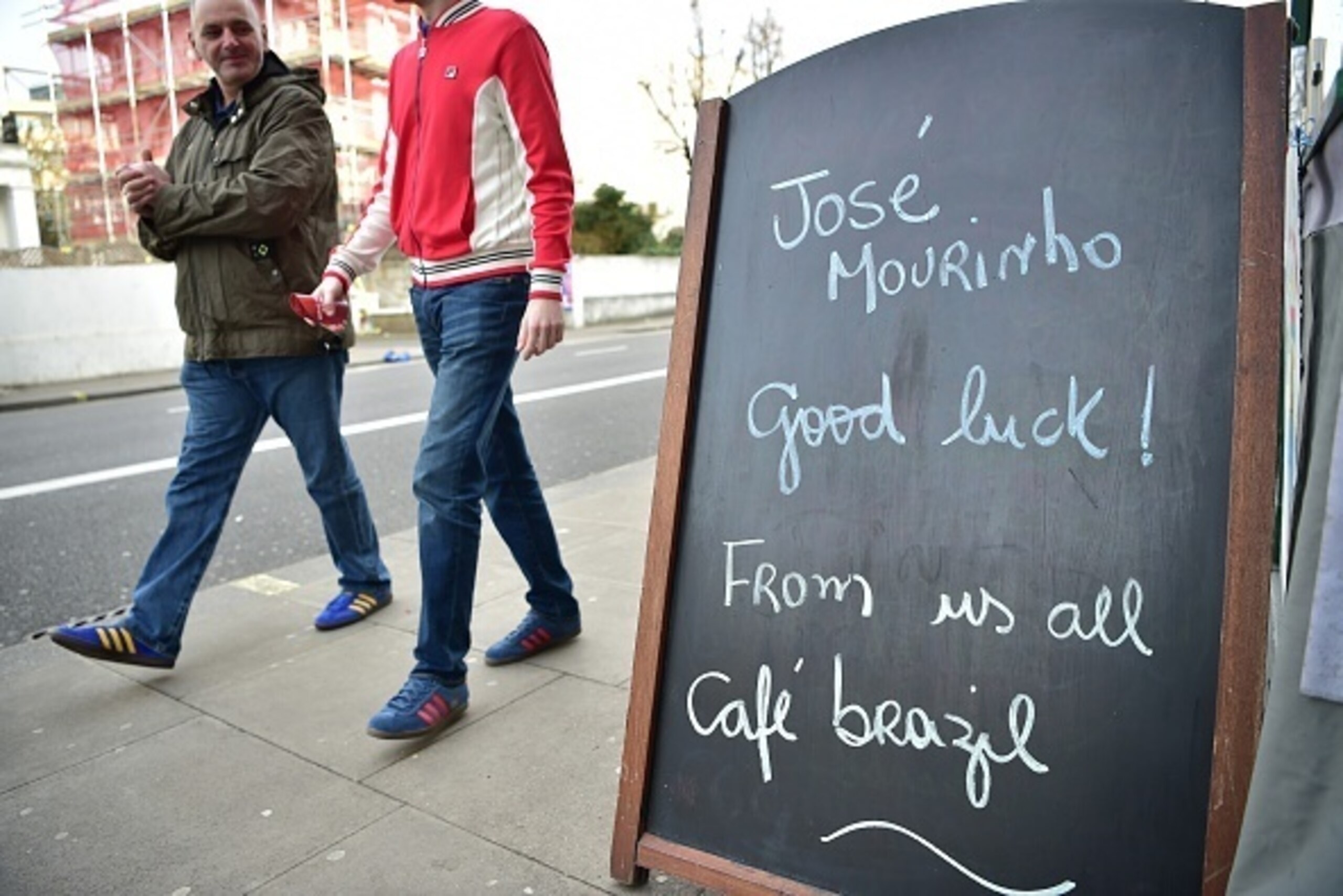 Football fans walk past a chalkboard of a cafe wishing Chelsea's former Portuguese manager Jose Mourinho good luck before the English Premier League football match between Chelsea and Sunderland at Stamford Bridge in London on December 19, 2015. Jose Mour