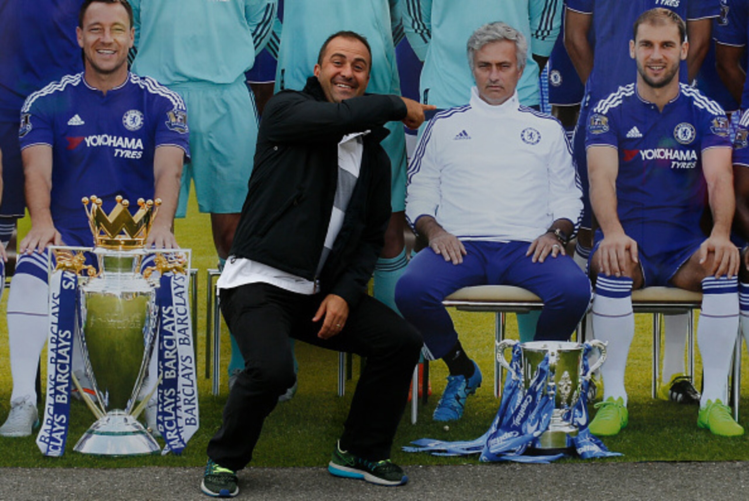 A man poses by a picture of the Chelsea team and points to Chelsea's former Portuguese manager Jose Mourinho before the English Premier League football match between Chelsea and Sunderland at Stamford Bridge in London on December 19, 2015. 
AFP PHOTO / IK