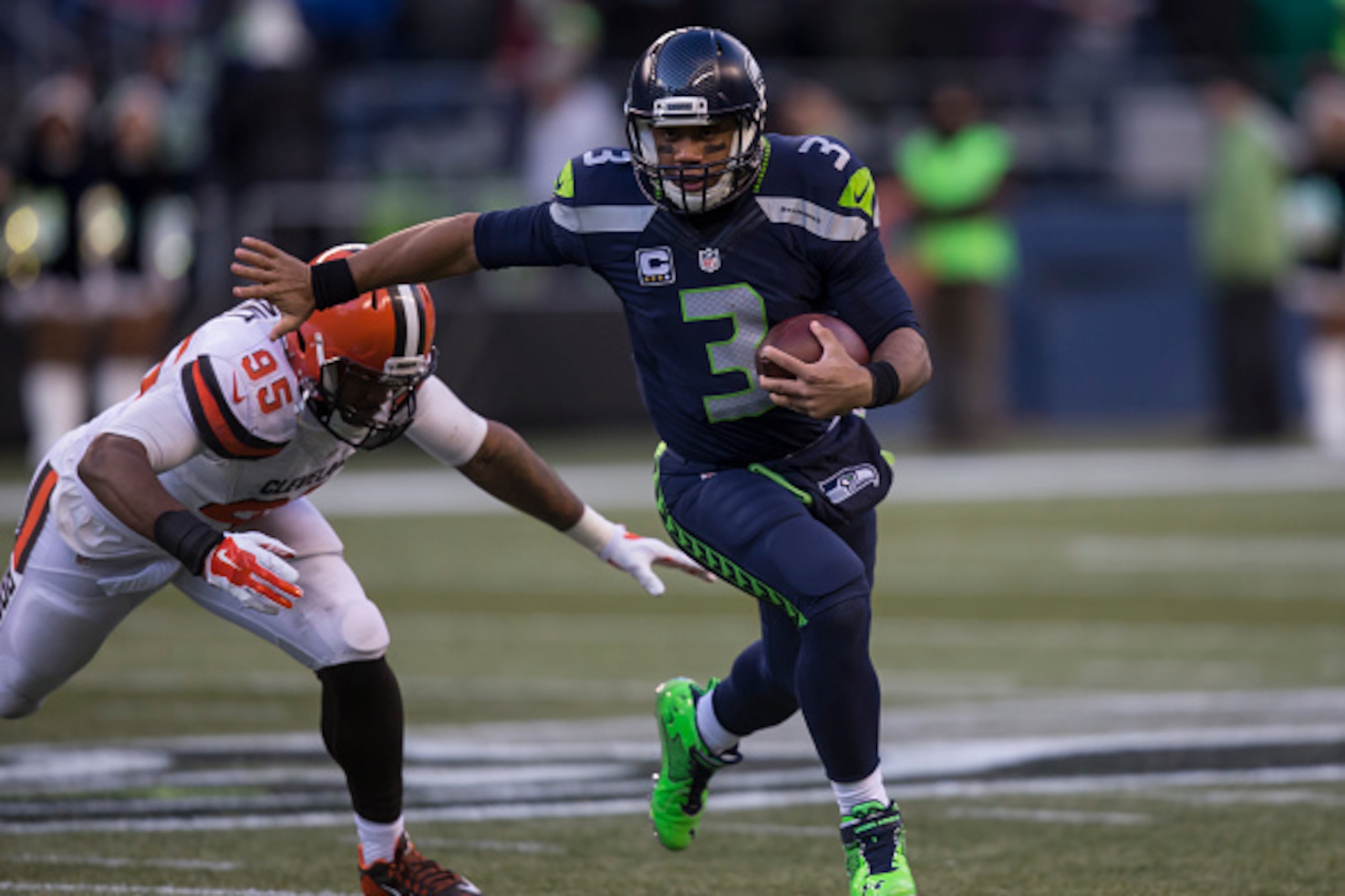 SEATTLE, WA - DECEMBER 20: Quarterback Russell Wilson #3 of the Seattle Seahawks runs with the ball as defensive lineman Armonty Bryant #95 of the Cleveland Browns tries to make the tackle during second half of a football game at CenturyLink Field on Dece