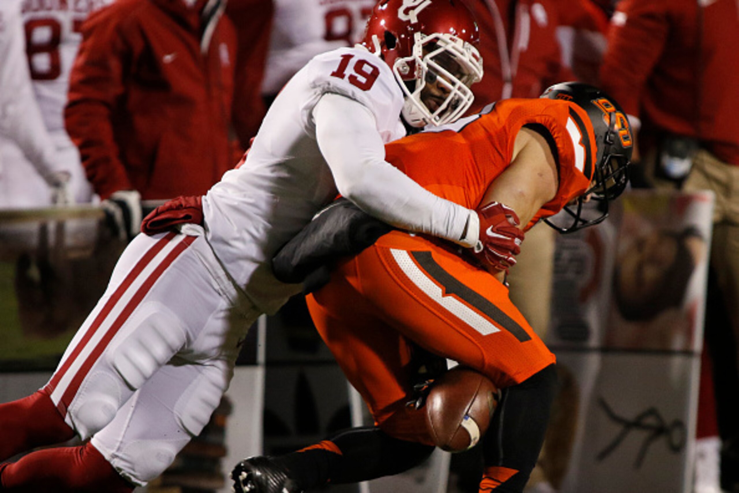 STILLWATER, OK - NOVEMBER 28 : Linebacker Eric Striker #19 of the Oklahoma Sooners hits wide receiver David Glidden #13 of the Oklahoma State Cowboys and causes a fumble November 28, 2015 at Boone Pickens Stadium in Stillwater, Oklahoma. Oklahoma defeated