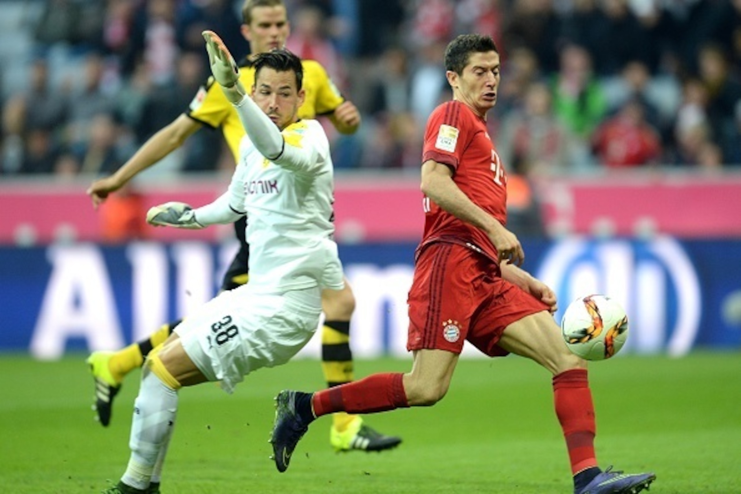 Bayern Munich's Polish striker Robert Lewandowski (R) scores the third goal for Munich against Dortmund's Swiss goalkeeper Roman Buerki (L) during the German first division Bundesliga football match FC Bayern Munich vs Borussia Dortmund in Munich, souther