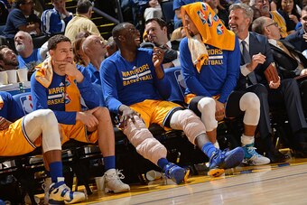 OAKLAND, CA - NOVEMBER 24:  Klay Thompson #11, Draymond Green #23 and Stephen Curry #30 of the Golden State Warriors sit on the bench during the game against the Los Angeles Lakers on November 24, 2015 at ORACLE Arena in Oakland, California. NOTE TO USER:
