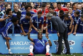 Chelsea's Serbian midfielder Nemanja Matic (top C) and Chelsea's Portuguese manager Jose Mourinho (R) place the crown of the Premier League trophy on the head of Chelsea's Ivorian striker Didier Drogba (bottom C) surrounded by team-mates during the trophy
