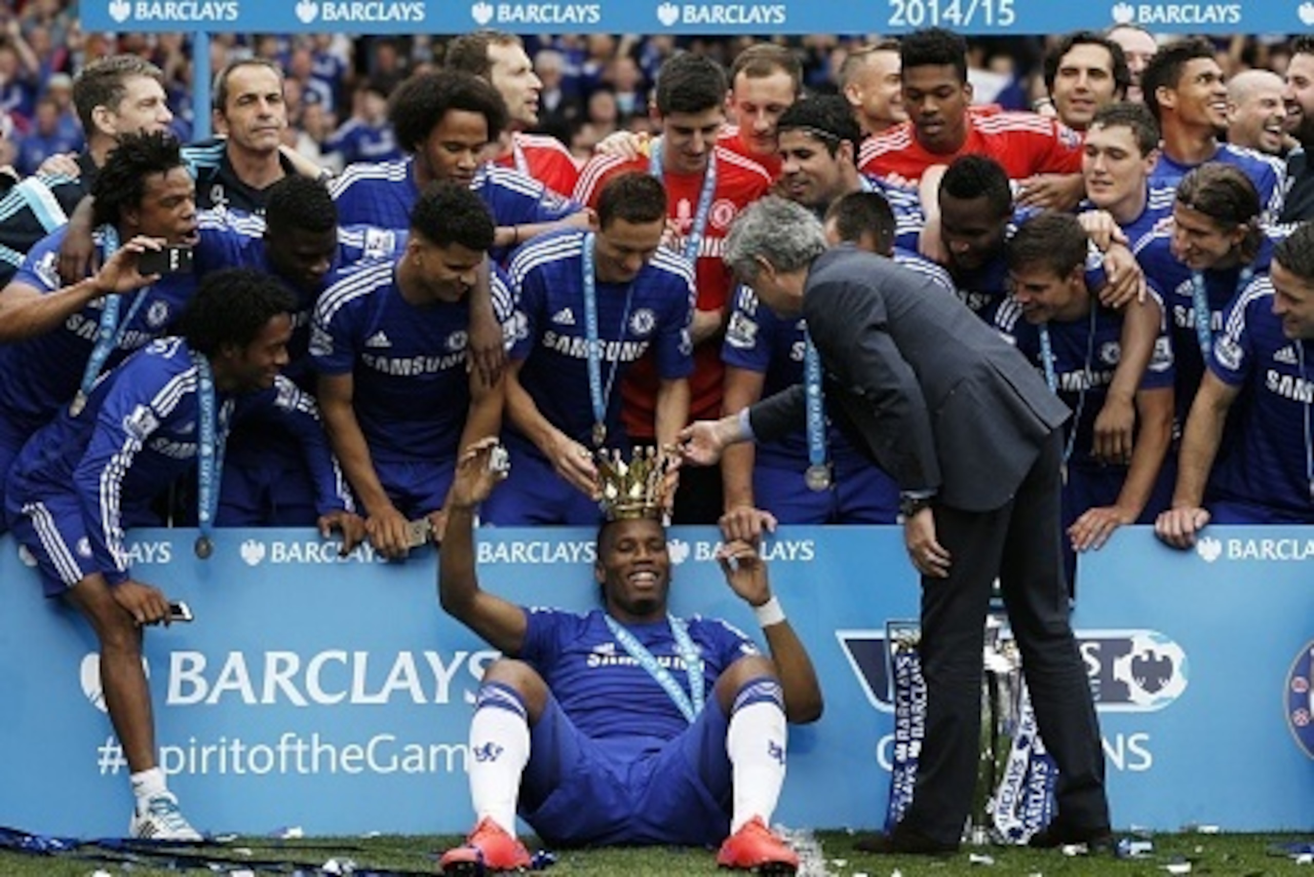 Chelsea's Serbian midfielder Nemanja Matic (top C) and Chelsea's Portuguese manager Jose Mourinho (R) place the crown of the Premier League trophy on the head of Chelsea's Ivorian striker Didier Drogba (bottom C) surrounded by team-mates during the trophy
