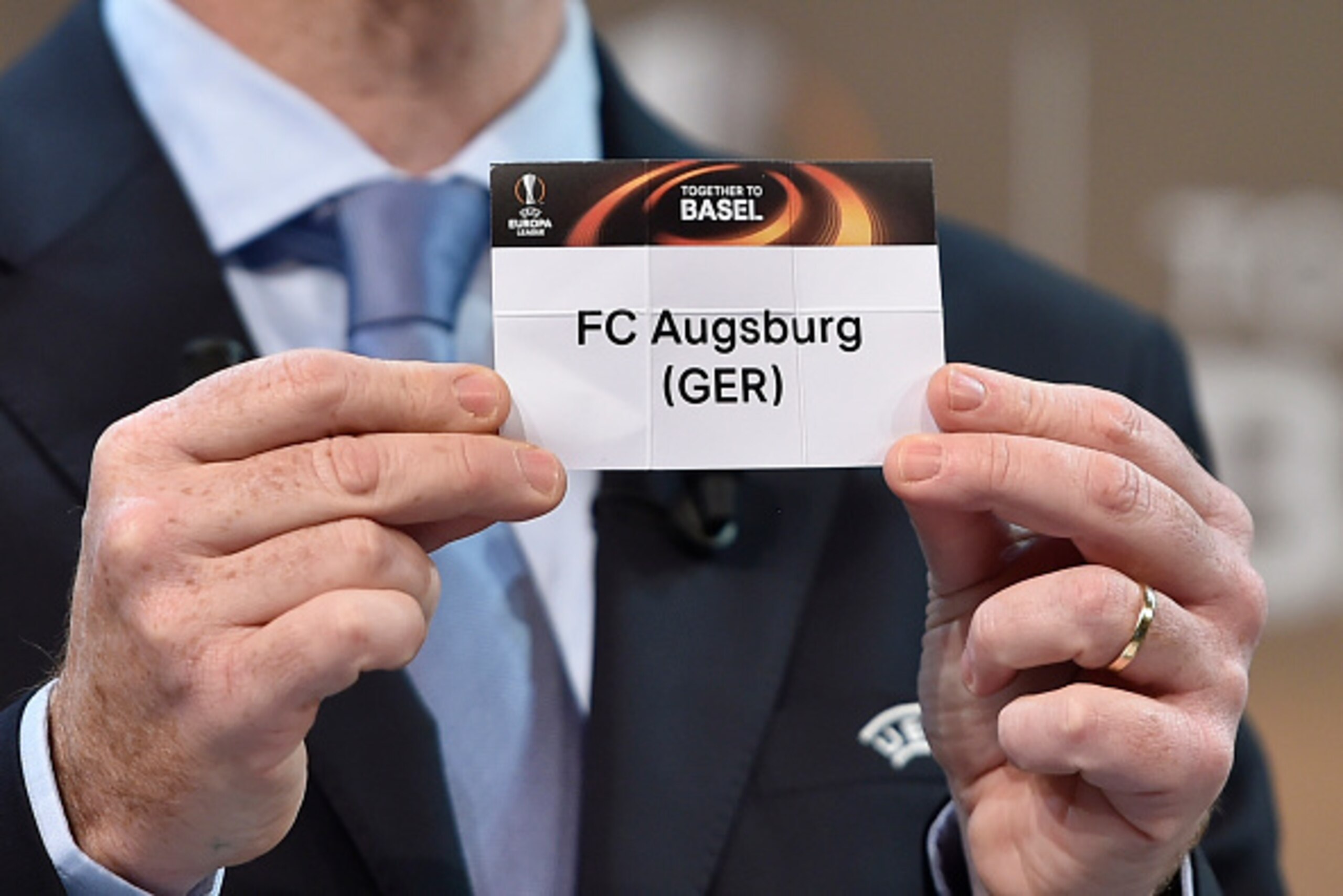 UEFA General Secretary  Gianni Infantino shows the name of FC Augsburg football club during  the draw for  the UEFA Europa league round of sixteen, on December 14, 2015 at the UEFA headquarters in Nyon.  AFP PHOTO / FABRICE COFFRINI / AFP / FABRICE COFFRI