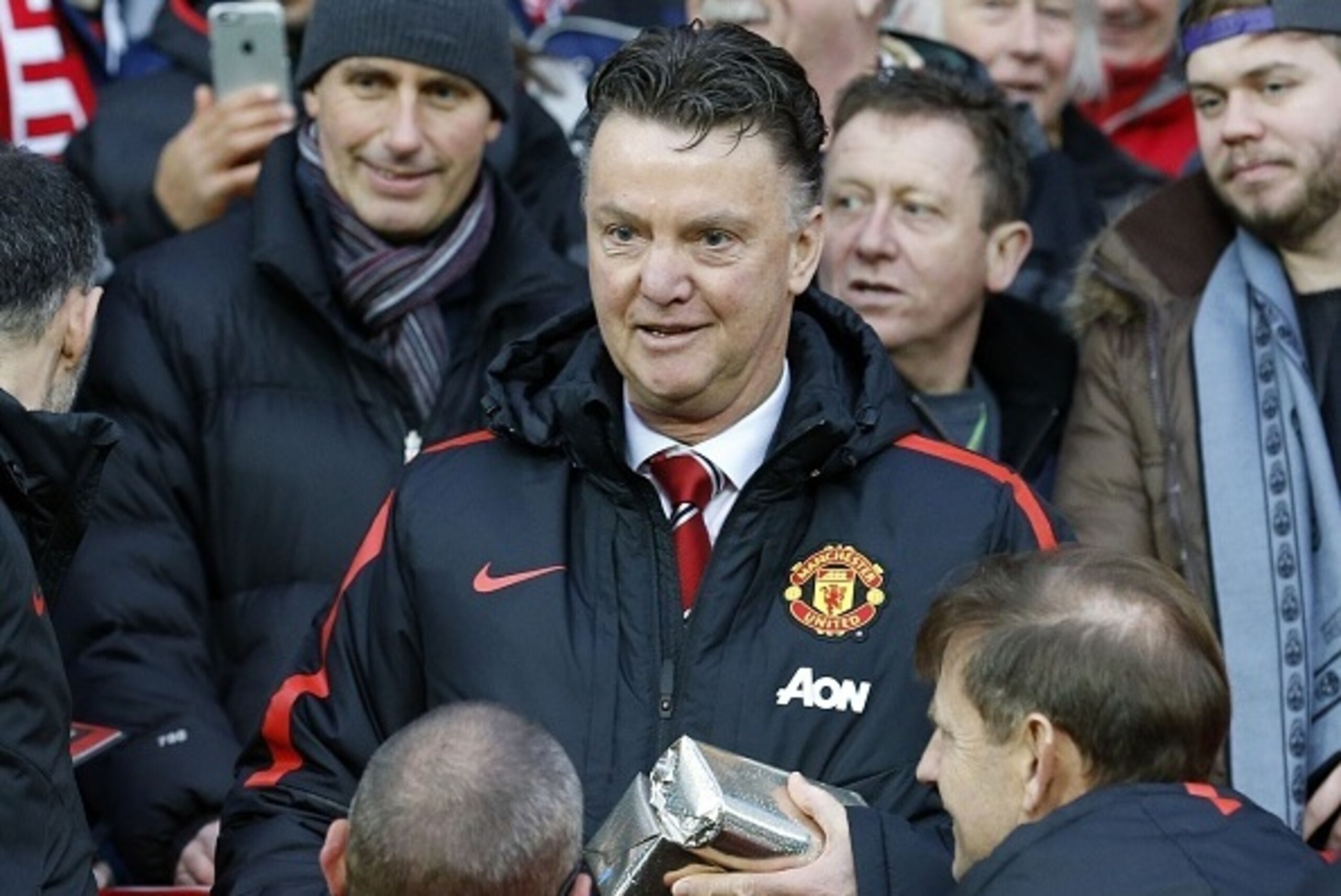 Manchester United's Dutch manager Louis van Gaal hands out Christmas presents to fans before during the English Premier League football match between Manchester United and Newcastle United at Old Trafford in Manchester, north west England, on December 26,