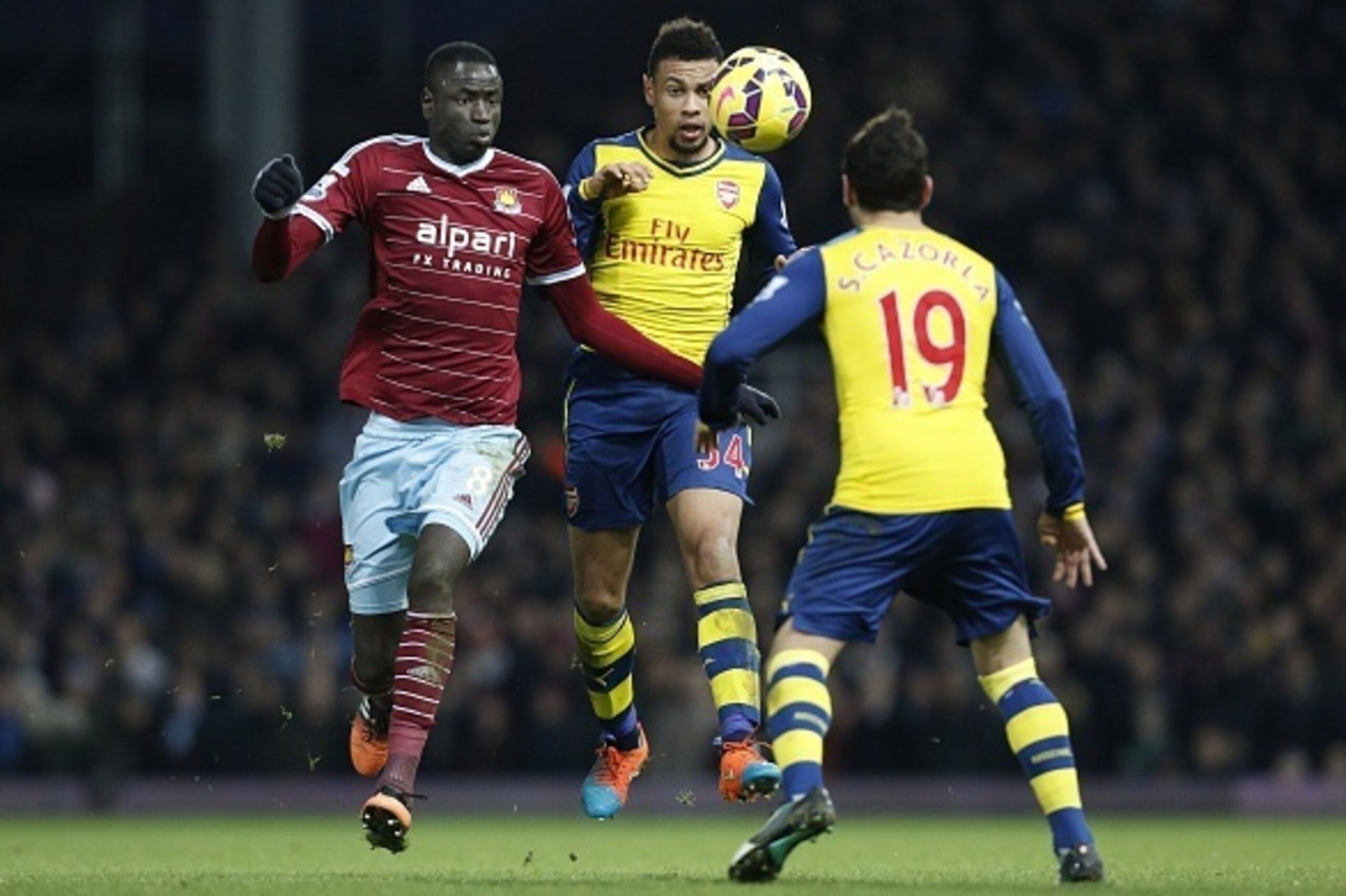 West Ham United's Senegalese midfielder Cheikhou Kouyate (L), Arsenal's French midfielder Francis Coquelin (C) and Arsenal's Spanish midfielder Santi Cazorla (R) go in for the ball during the English Premier League football match between West Ham United a