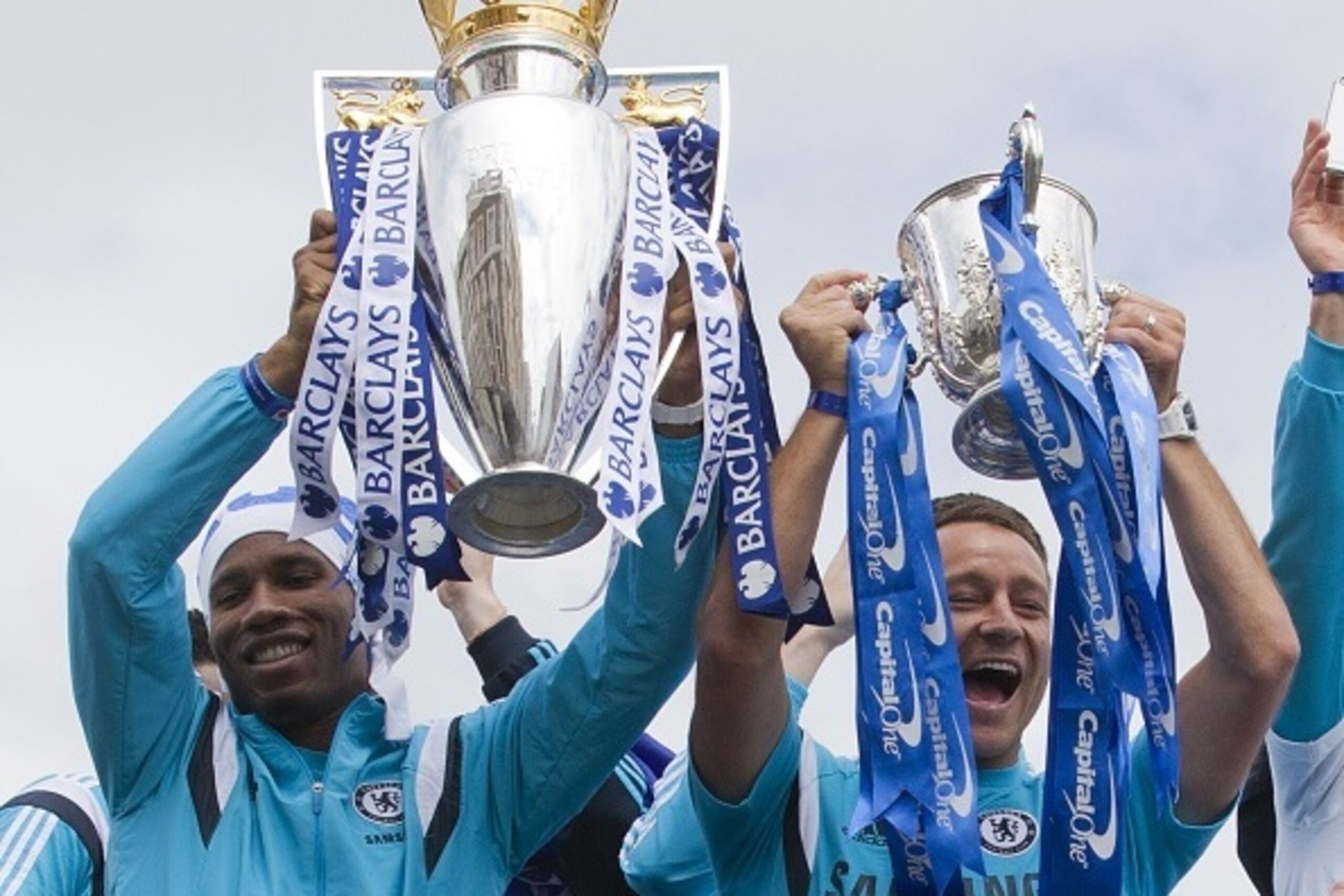 Chelsea's Ivorian striker Didier Drogba (L) holds up the Premier league trophy as Chelsea's English defender John Terry holds up the League cup as they leave Stamford Bridge stadium to take part in an open-top bus parade to celebrate winning the league in