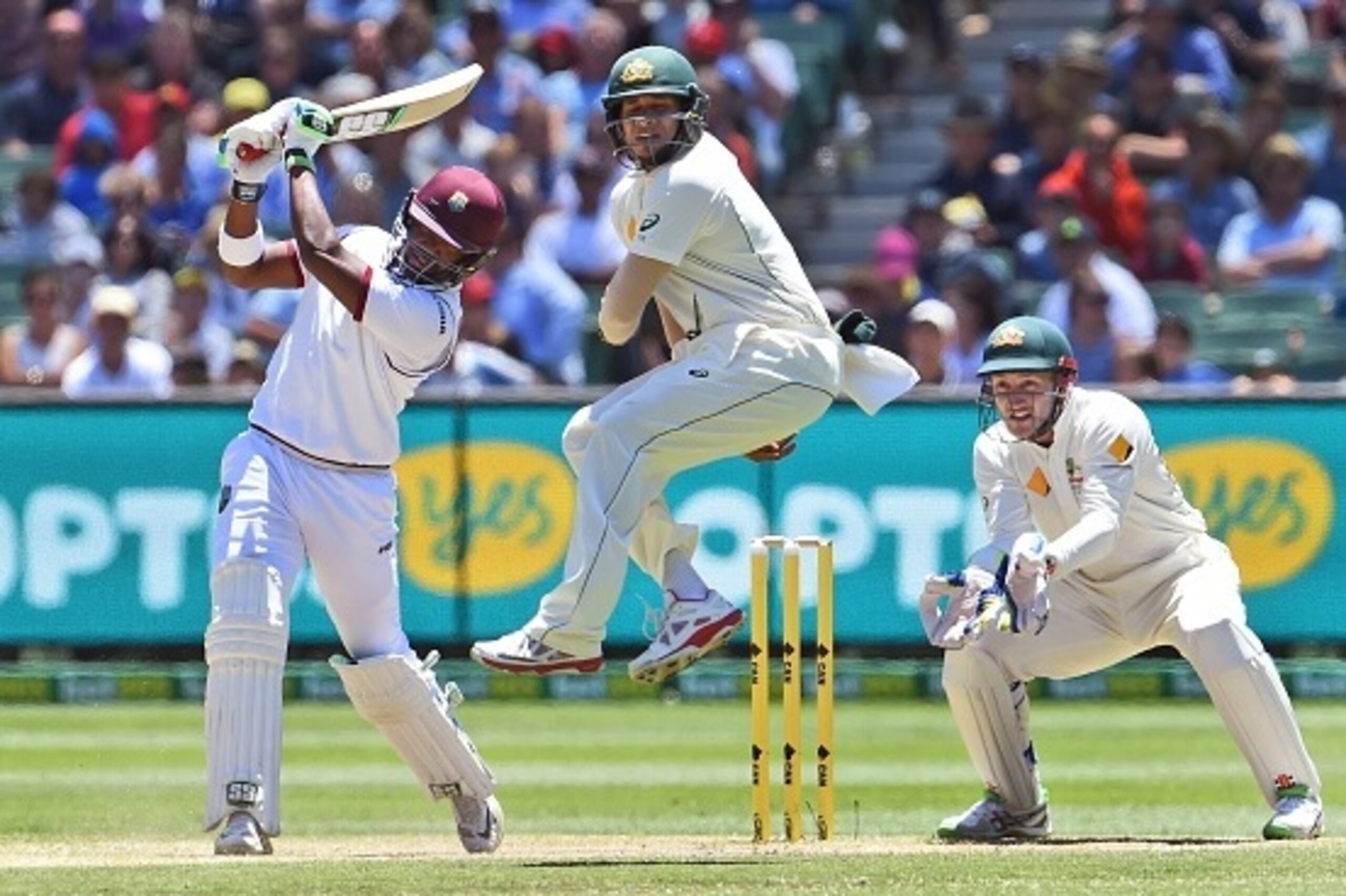 West Indies batsman Darren Bravo (L) slams a ball past Australia fieldsman Usman Khawaja (C) as wicketkeeper Peter Nevill (R) looks on, on the third day of the second cricket Test in Melbourne on December 28, 2015.    AFP PHOTO / William WEST   
--IMAGE R
