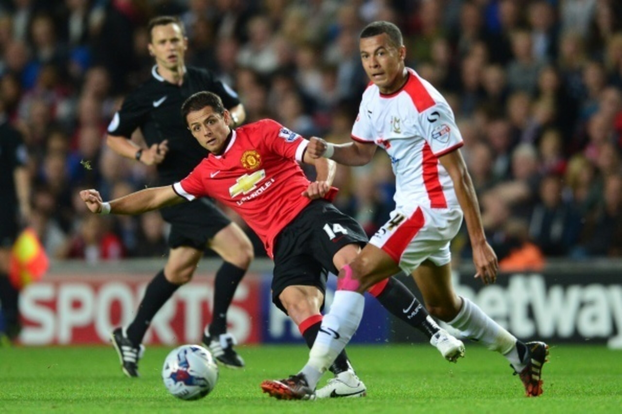 Manchester United's Mexican striker Javier Hernandez (L) passes the ball behind MK Dons English midfielder Dele Alli during the English League Cup second round football match between Milton Keynes Dons and Manchester United at Stadium MK in Milton Keynes,