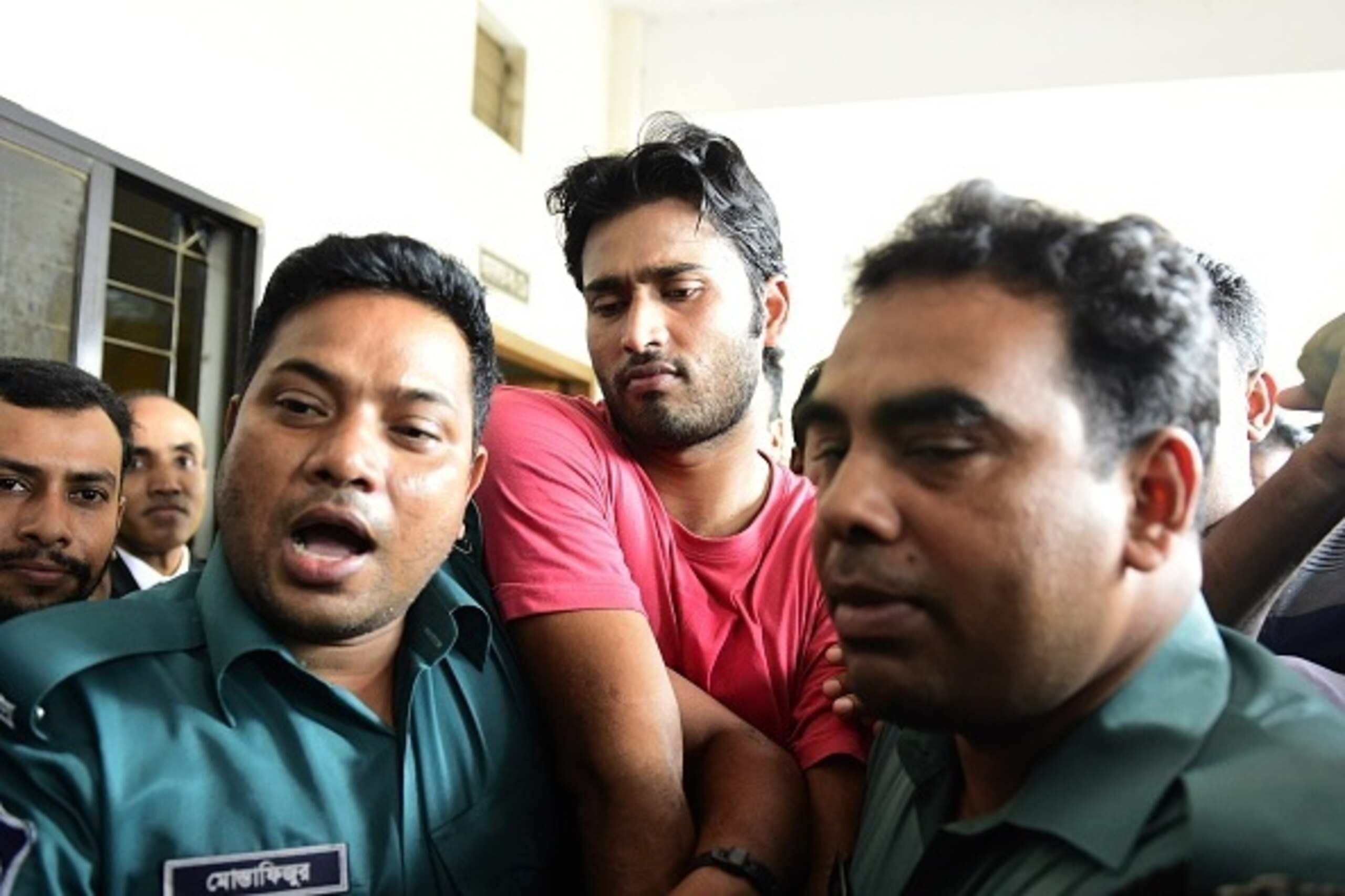 Bangladeshi security personnel escort fugitive cricketer Shahadat Hossain (C) after he surrendered in Dhaka on October 5, 2015. Hossain was remanded in jail on October 5 shortly after he surrendered to a court over allegations of beating his 11-year-old m