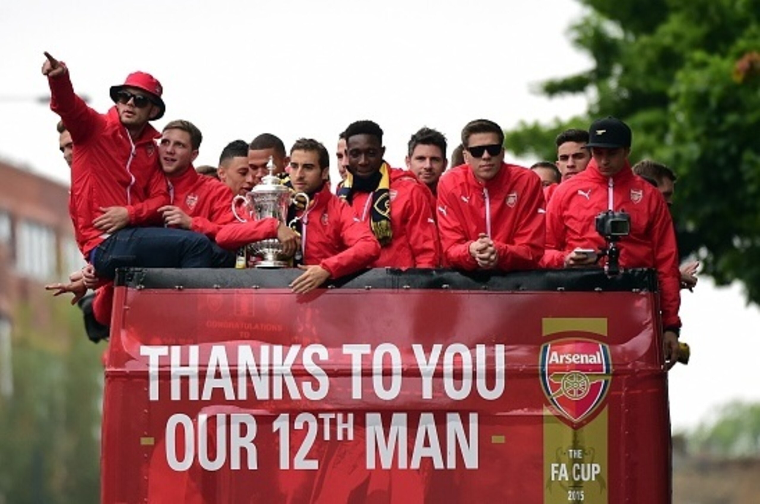 Arsenal's French midfielder Mathieu Flamini (6L) holds the trophy as he travels with teammates on the top deck of an open-topped bus during the Arsenal victory parade in London on May 31, 2015, following their win in the English FA Cup final football matc