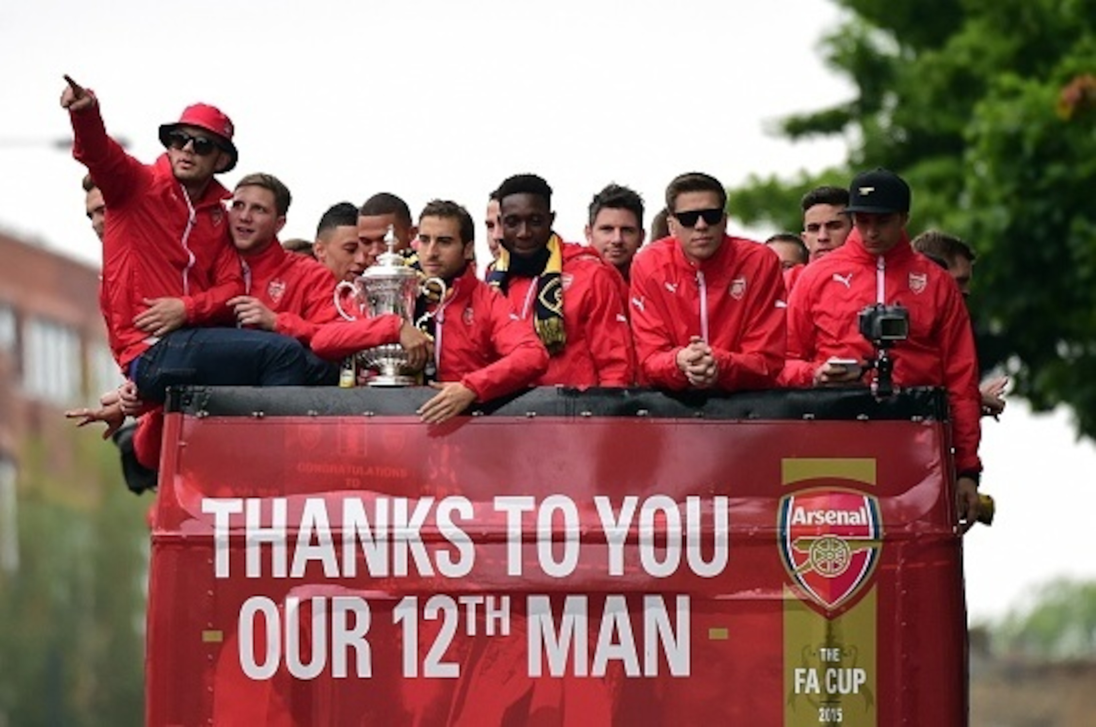 Arsenal's French midfielder Mathieu Flamini (6L) holds the trophy as he travels with teammates on the top deck of an open-topped bus during the Arsenal victory parade in London on May 31, 2015, following their win in the English FA Cup final football matc
