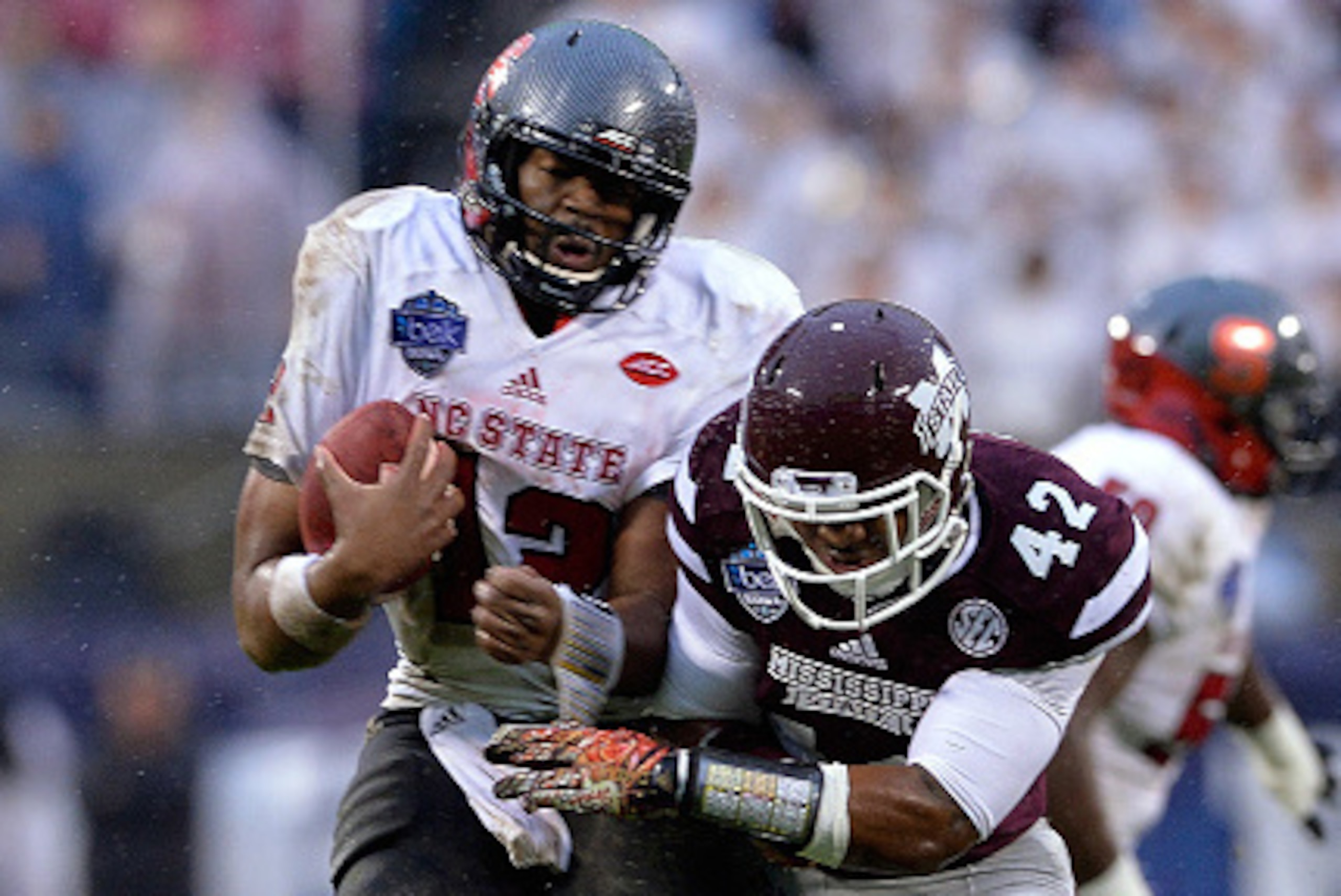 CHARLOTTE, NC - DECEMBER 30:  Jacoby Brissett #12 of the North Carolina State Wolfpack collides with Beniquez Brown #42 of the Mississippi State Bulldogs during the Belk Bowl at Bank of America Stadium on December 30, 2015 in Charlotte, North Carolina.  (