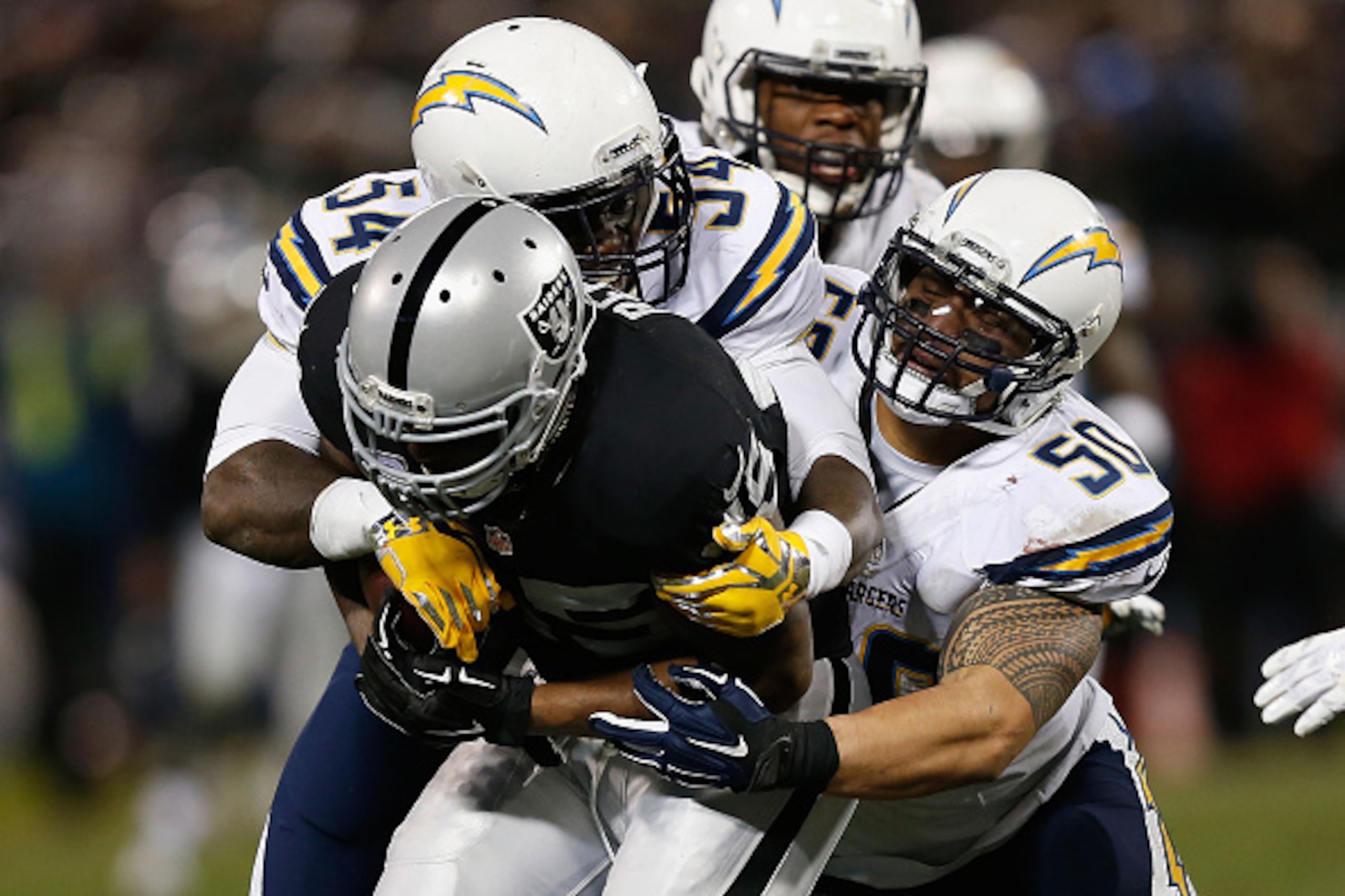 OAKLAND, CA - DECEMBER 24: Full back Marcel Reece #45 of the Oakland Raiders is tackled by linebackers Melvin Ingram #54 and Manti Te'o #50 of the San Diego Chargers in overtime at O.co Coliseum on December 24, 2015 in Oakland, California. (Photo by Lachl
