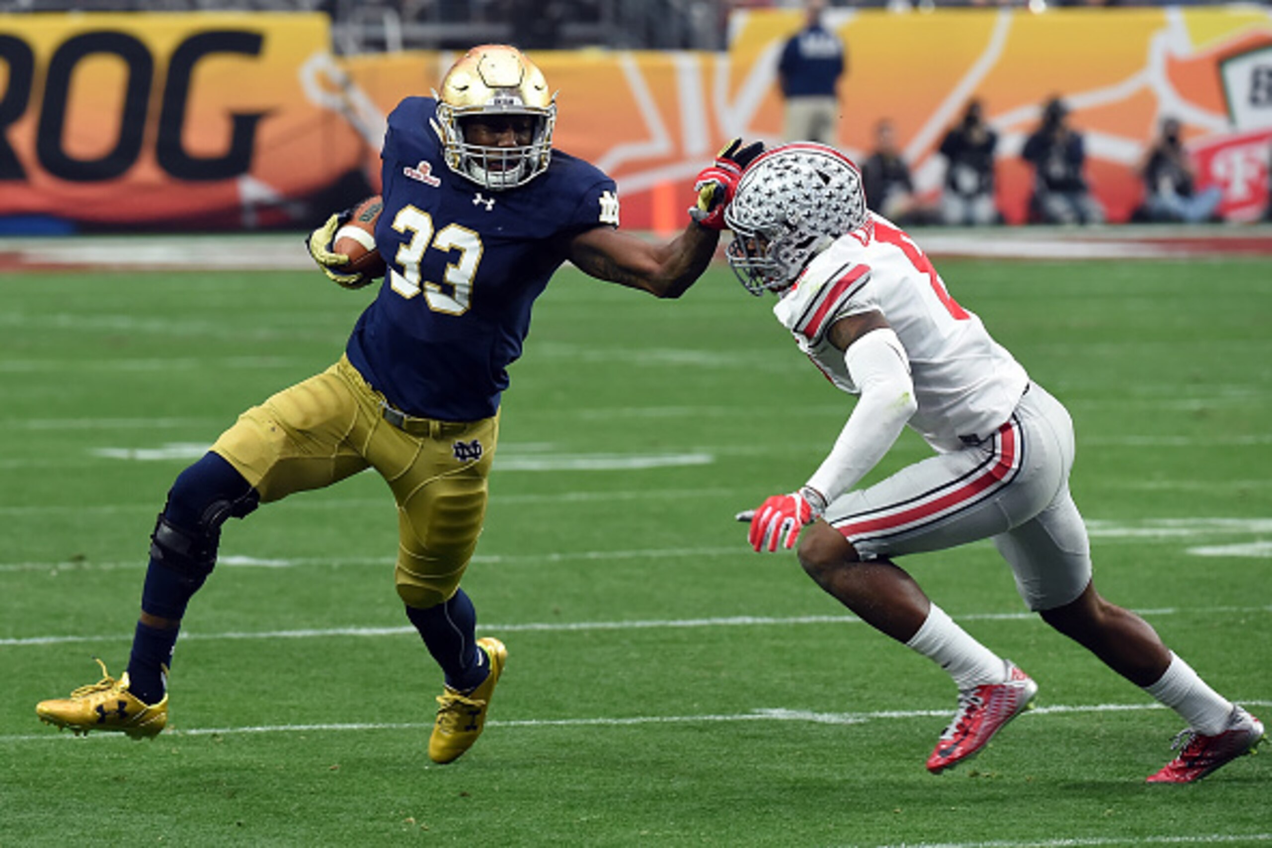 GLENDALE, AZ - JANUARY 01: Running back Josh Adams #33 of the Notre Dame Fighting Irish stiff arms cornerback Gareon Conley #8 of the Ohio State Buckeyes during the first quarter of the BattleFrog Fiesta Bowl at the University of Phoenix Stadium on Januar