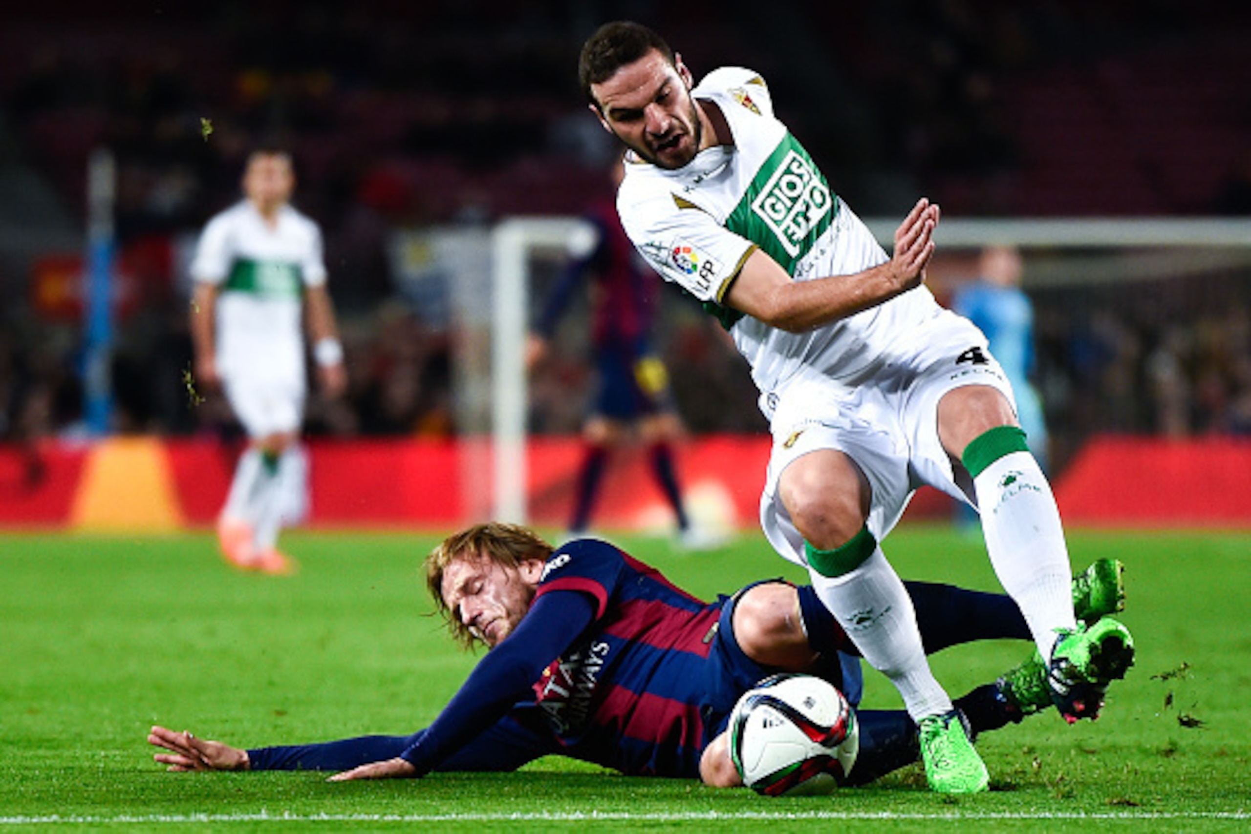 BARCELONA, SPAIN - JANUARY 08:  Ivan Rakitic of FC Barcelona is brought down by David Lomban of Elche FC during the Copa del Rey  Round of 16 First Leg match between FC Barcelona and Elche CF at Camp Nou on January 8, 2015 in Barcelona, Spain.  (Photo by 