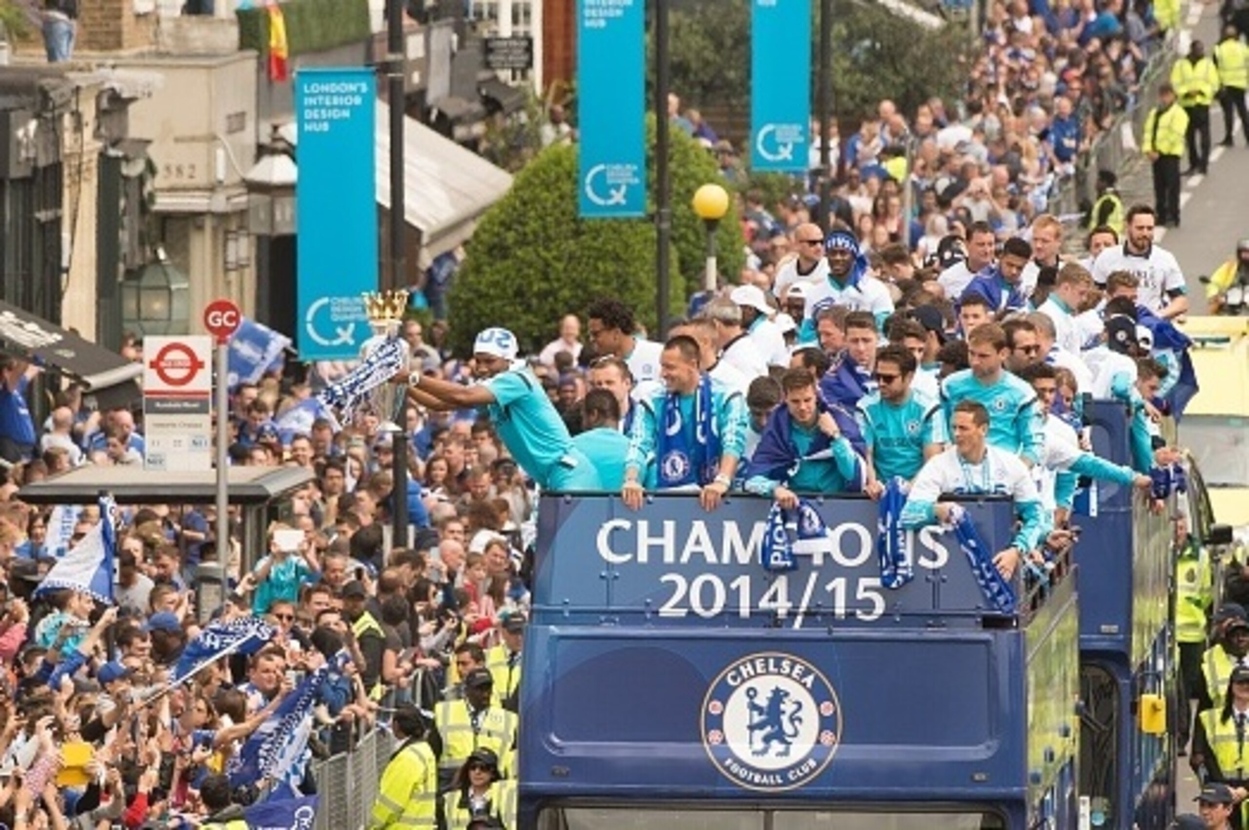 Chelsea's Ivorian striker Didier Drogba (L) holds up the Premier league trophy to fans as the Chelsea team take part in an open-top bus parade through Fulham, south-west London on May 25, 2015 to celebrate winning the Premier League title and the Capital 