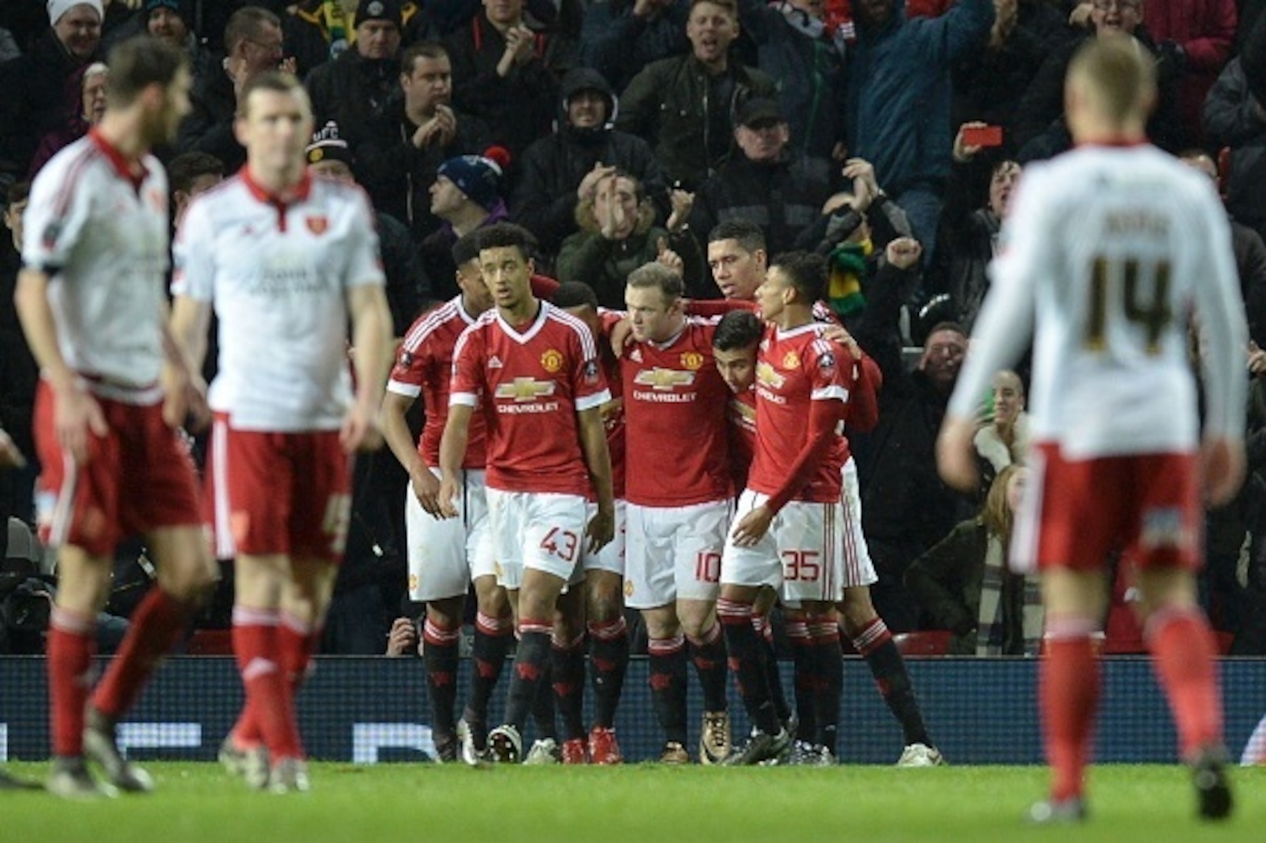 Manchester United's English striker Wayne Rooney (C) celebrates with team-mates after scoring from the penalty spot for the opening goal late during the English FA Cup third-round football match between Manchester United and Sheffield United at Old Traffo